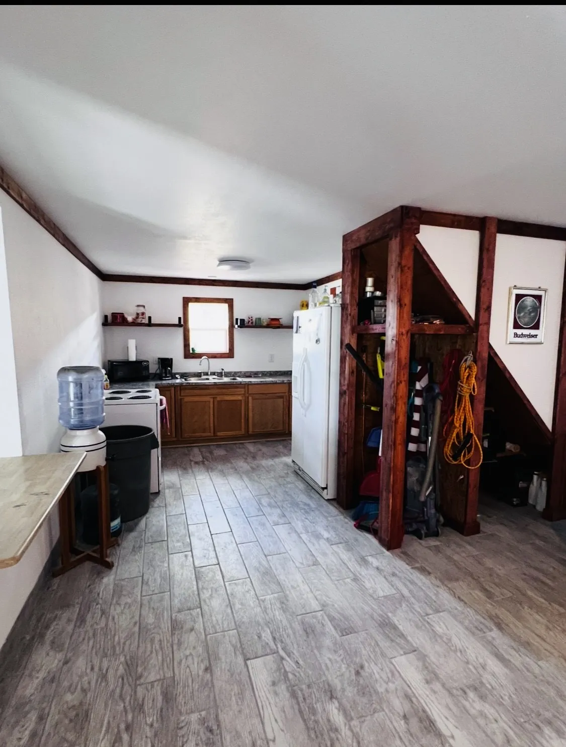 Kitchen featuring wood-finish flooring, wood cabinetry, a window, open shelving, and a built-in refrigerator