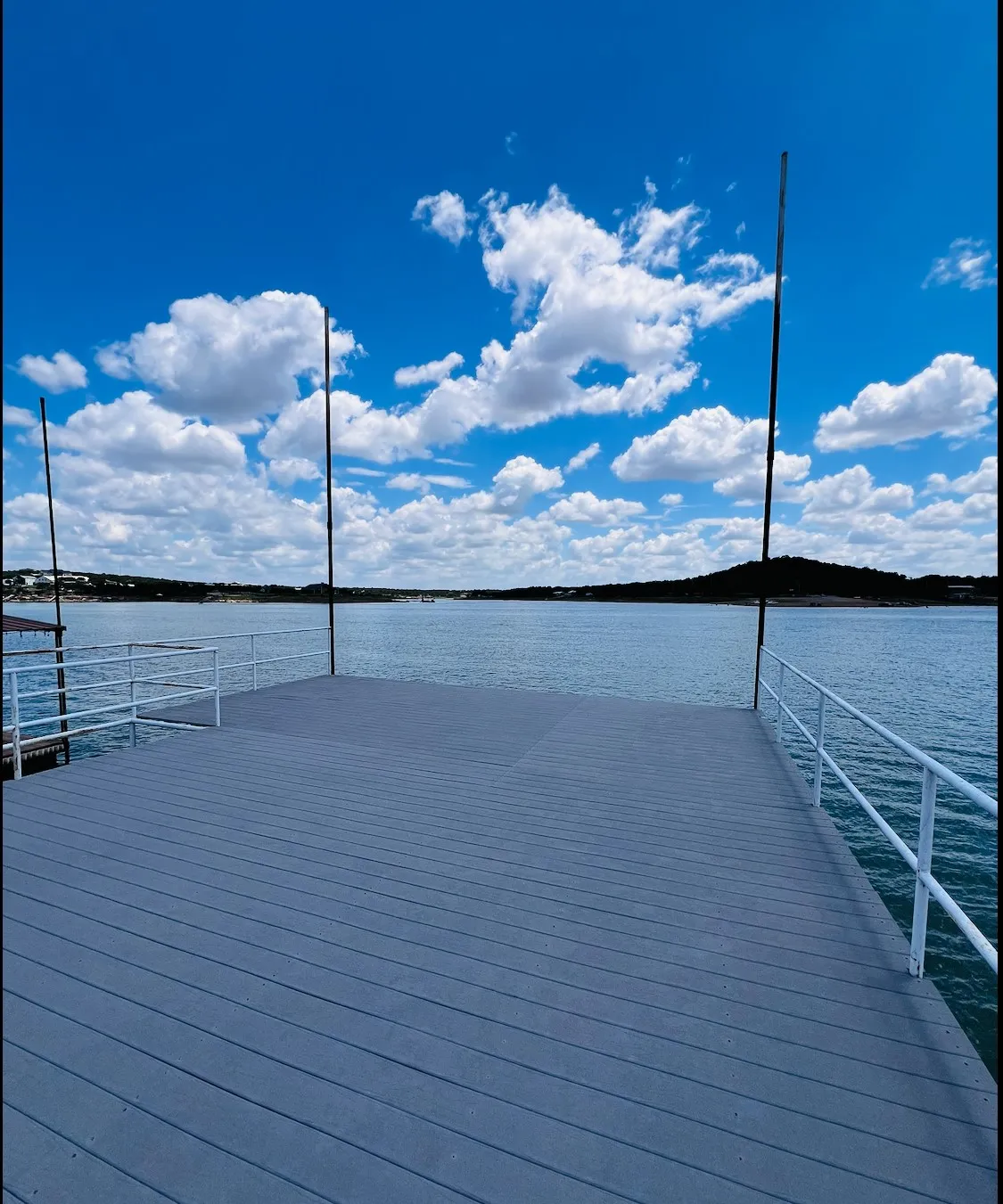 Expansive grey dock with white railings, offering direct water access and views of the distant shoreline
