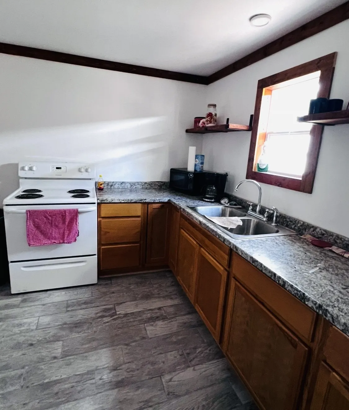 Kitchen featuring wood-finish cabinetry, speckled countertops, and a stainless-steel sink with a gooseneck faucet