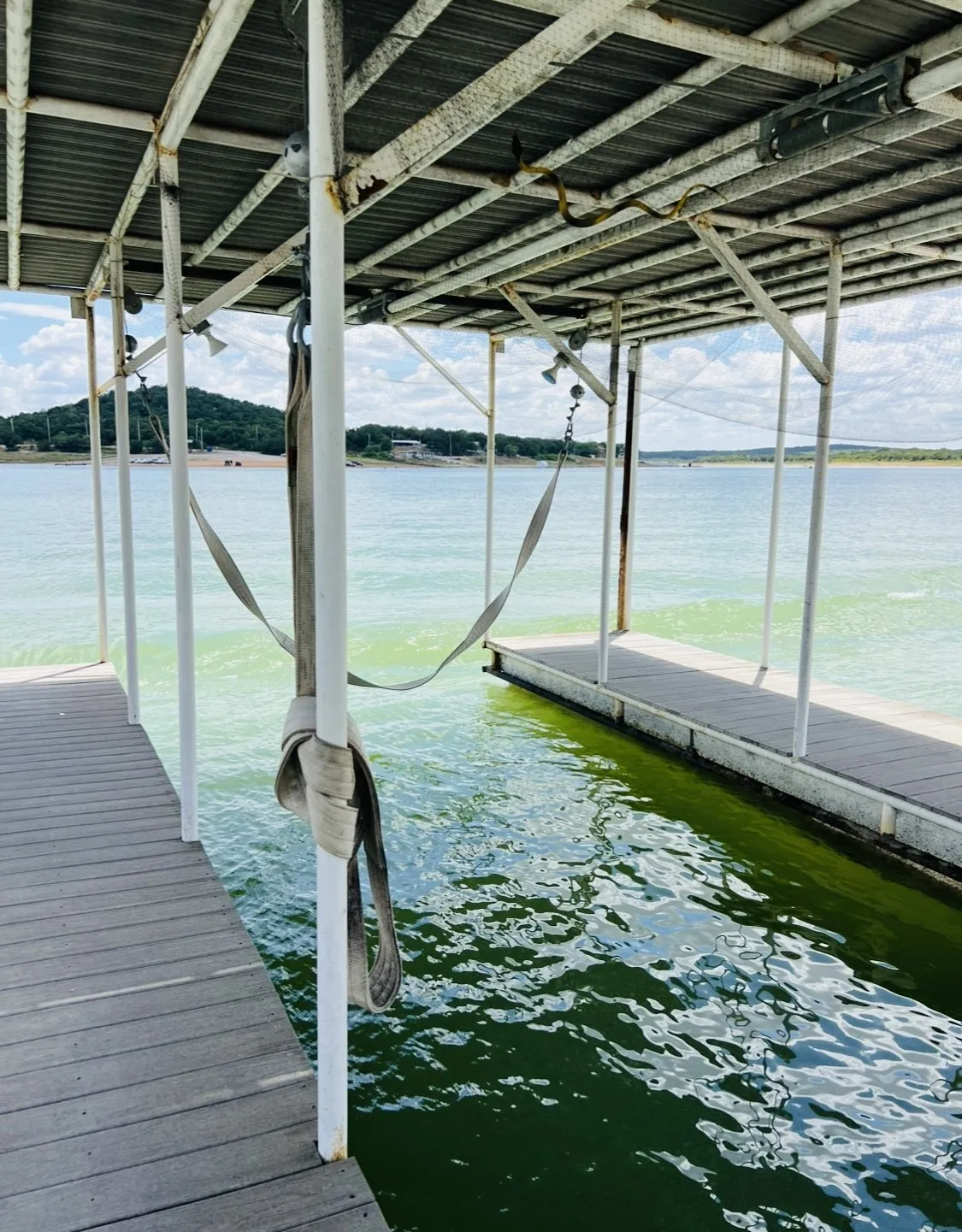 Covered boat dock featuring slip opening, grey composite decking, and a boat lift
