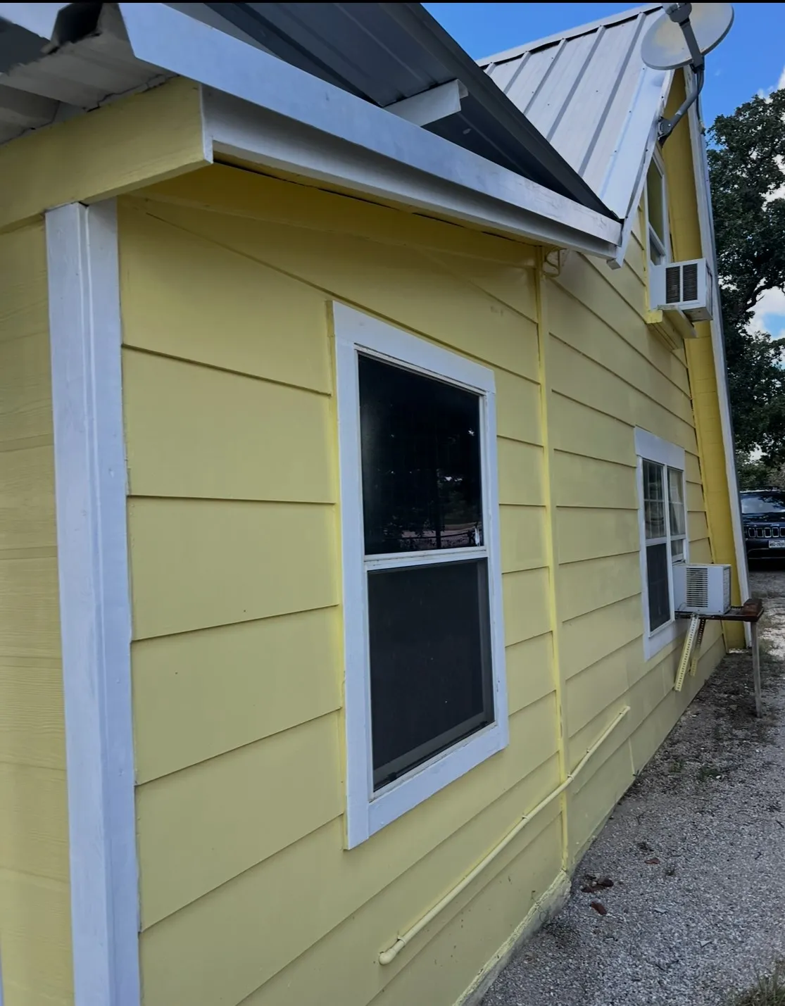 Yellow horizontal siding exterior with white window trim and a metal roof