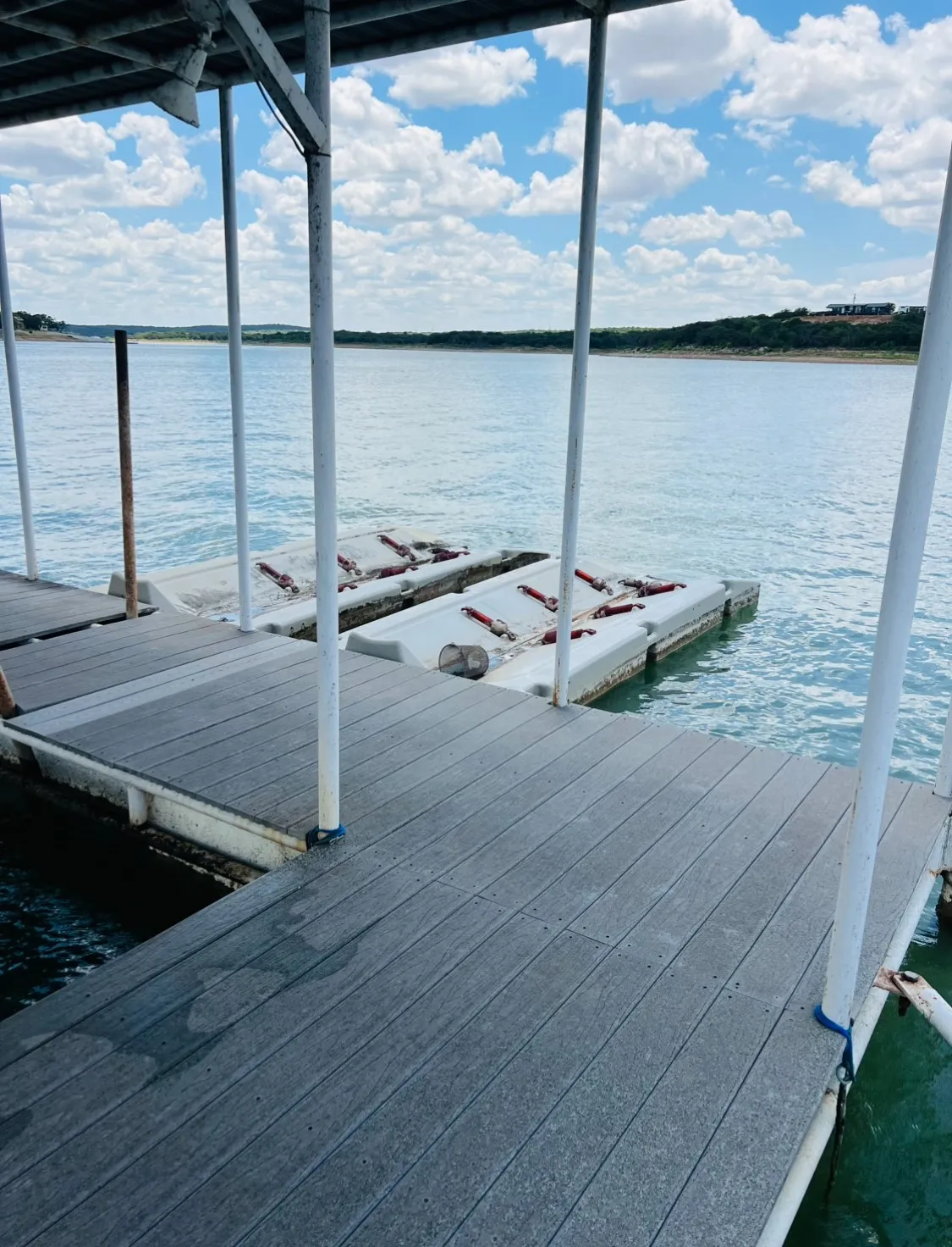 Floating dock with composite decking, featuring a covered structure with white support posts and jet ski parking.