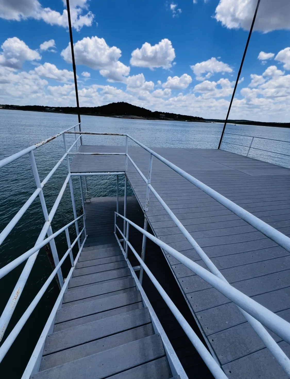 Private dock featuring composite decking, white metal railings, and direct water access