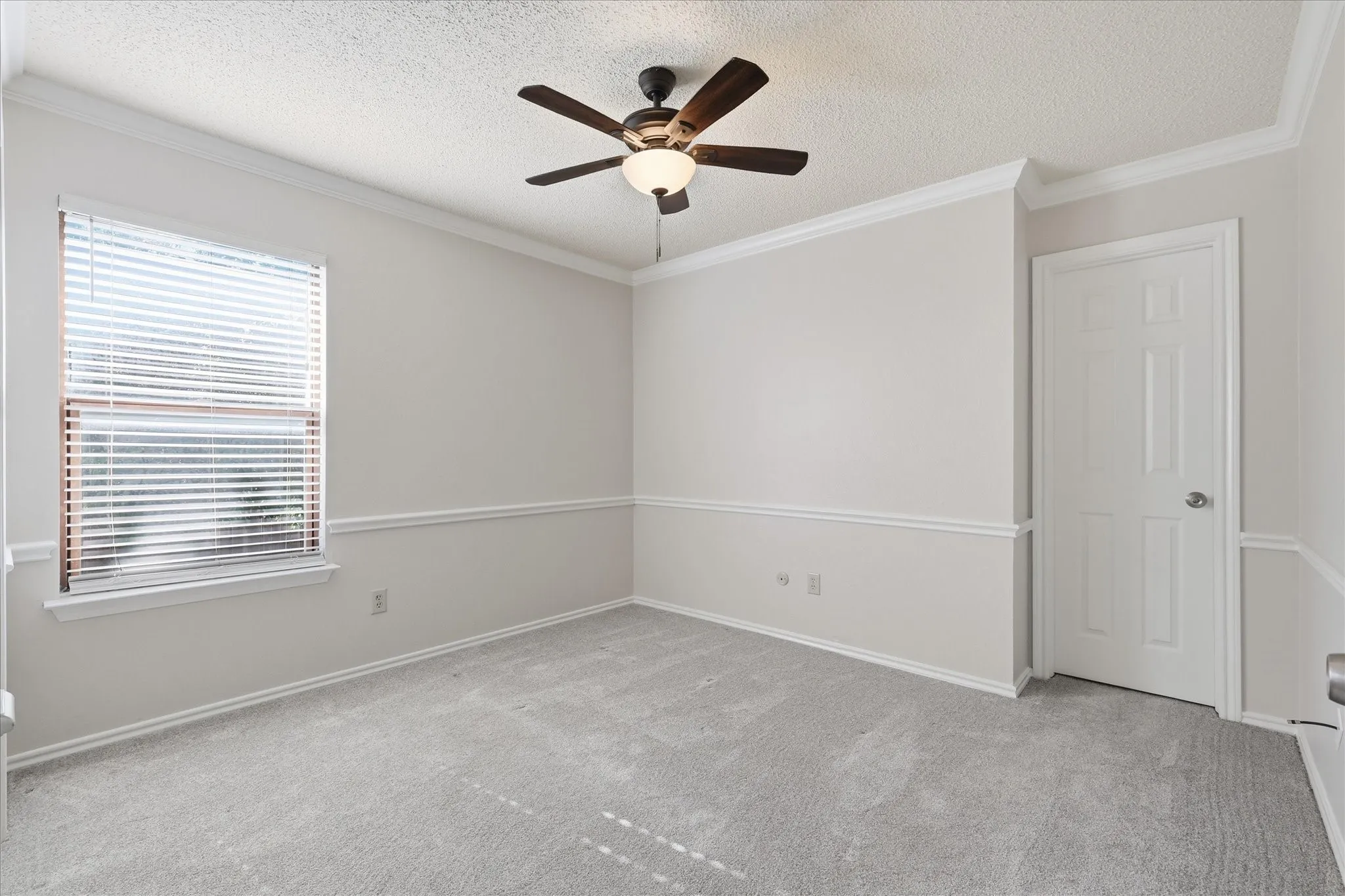 This comfortable secondary bedroom features fresh neutral tones, plush carpeting, crown molding and natural light.