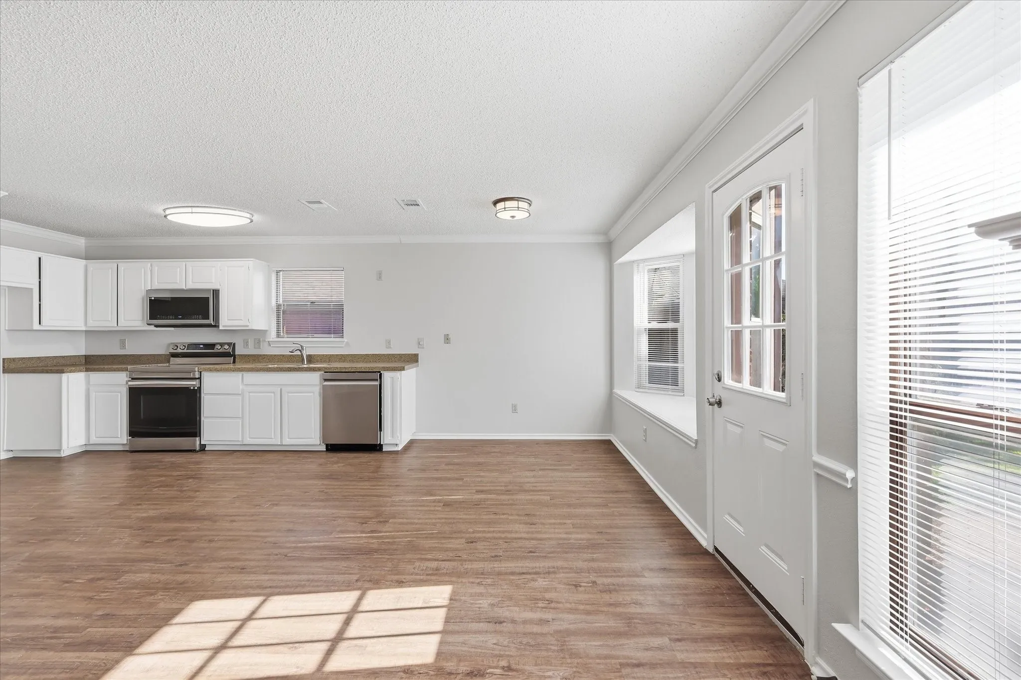 From the kitchen, enjoy an open sightline across the family room to the fireplace and sun-filled windows beyond