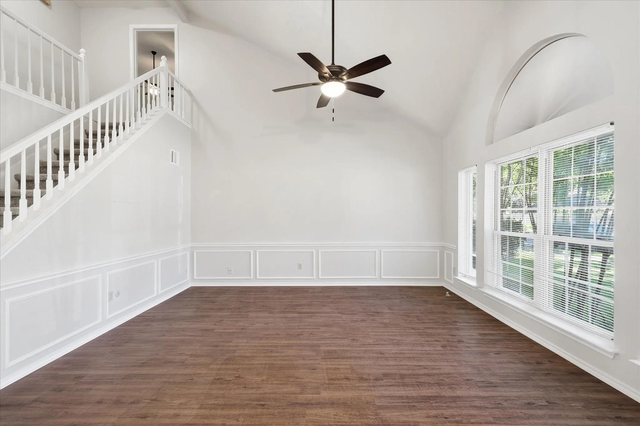 A sweeping staircase and dramatic ceiling height bring architectural interest to this bright and versatile living space.