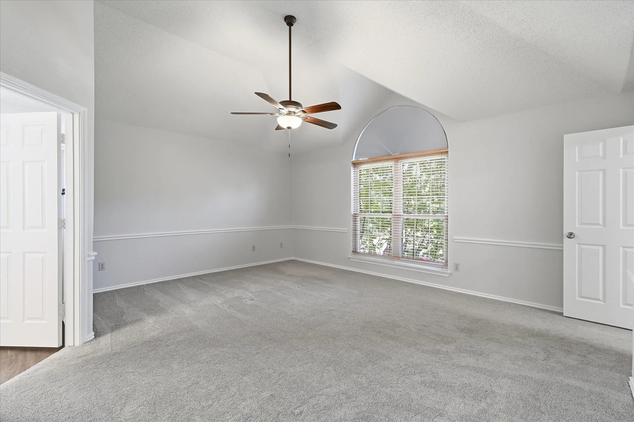 The oversized primary suite features a vaulted ceiling, large arched window and an abundance of space for a relaxing sitting area.