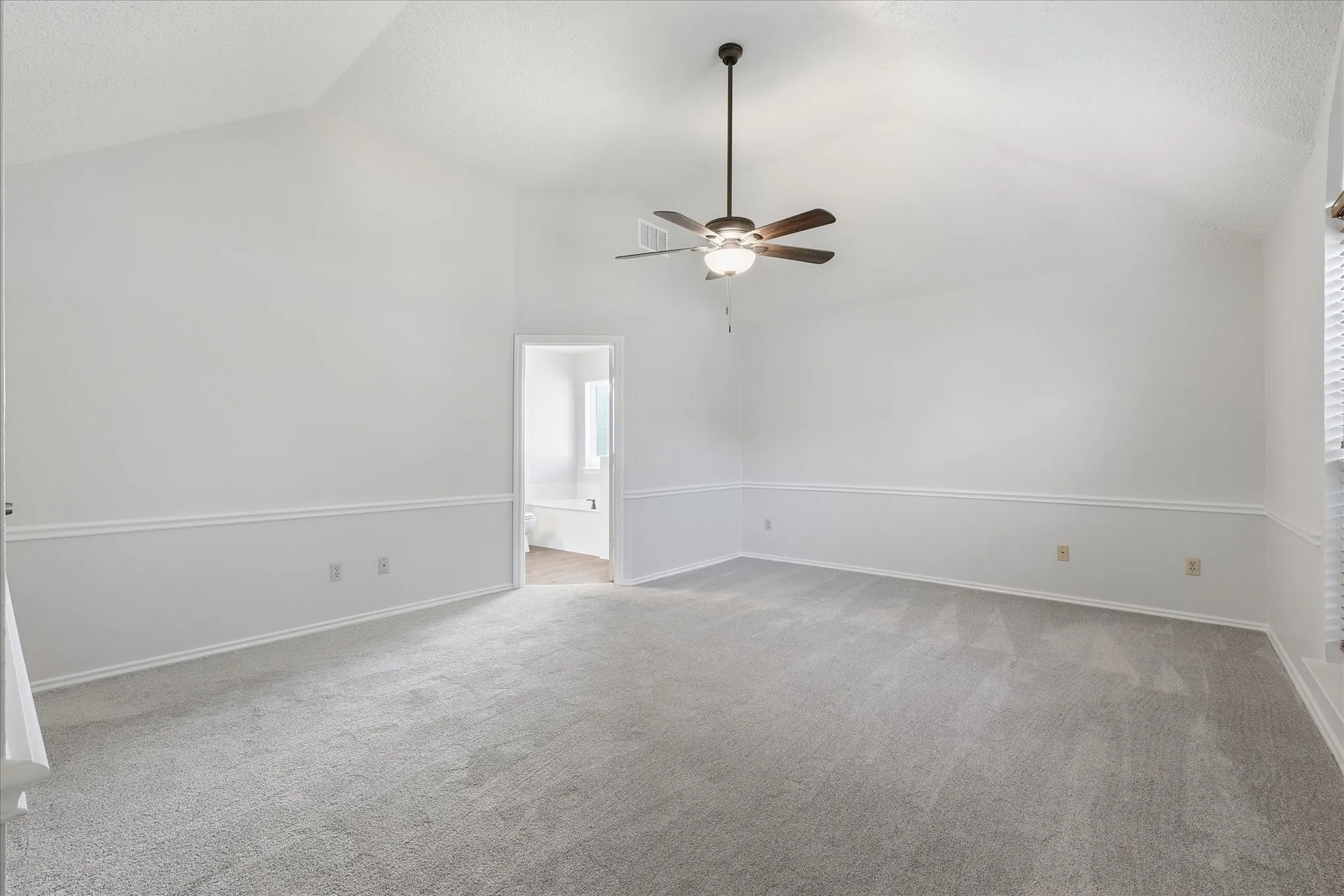 Retreat to a spacious primary bedroom with soaring ceilings, soft neutral finishes and direct access to the private bath.