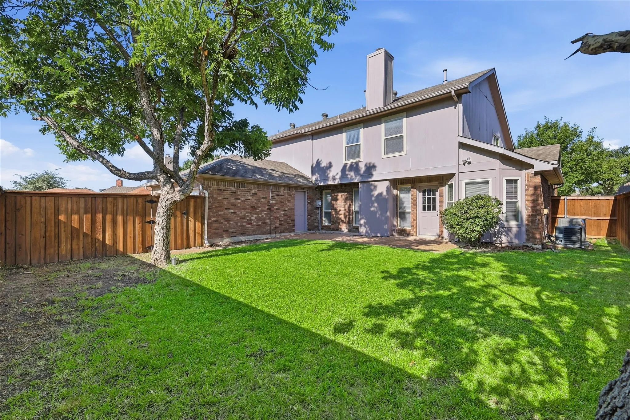 The spacious fenced yard provides a peaceful backdrop with mature trees, green lawn and direct access to the home.