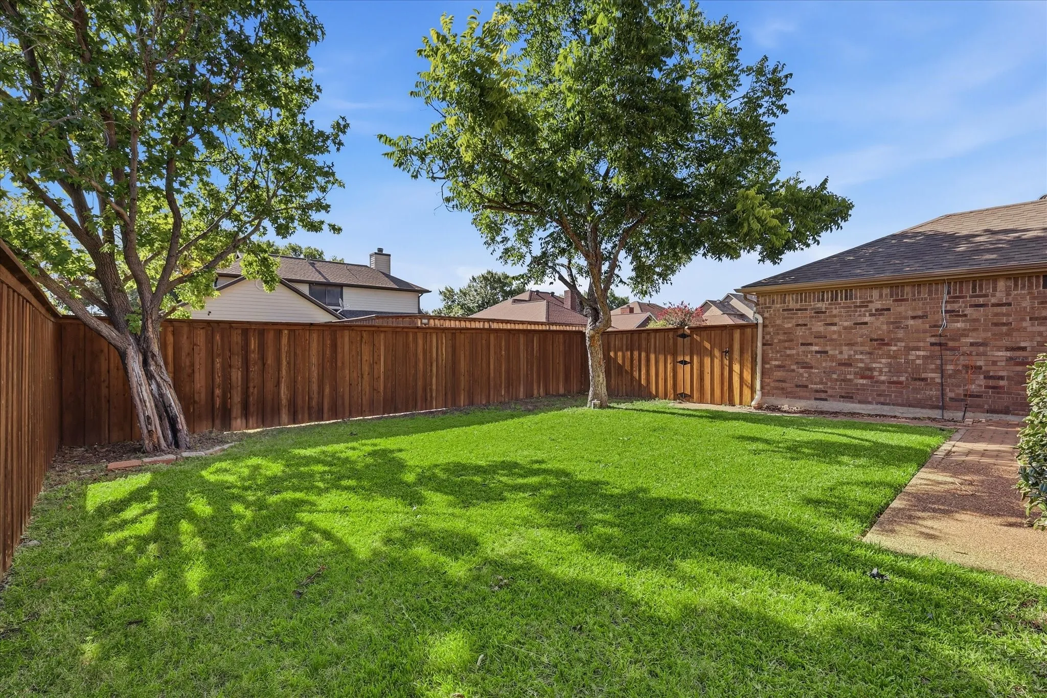 A generous, fully fenced backyard offers mature shade trees and ample space for play.
