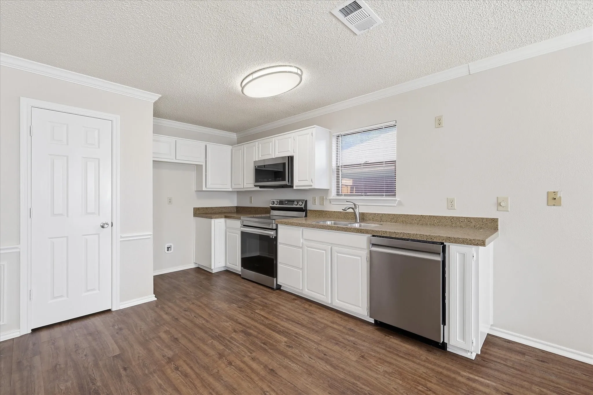 A spacious kitchen with white cabinetry, stainless appliances and generous open space for dining, entertaining and daily routines.
