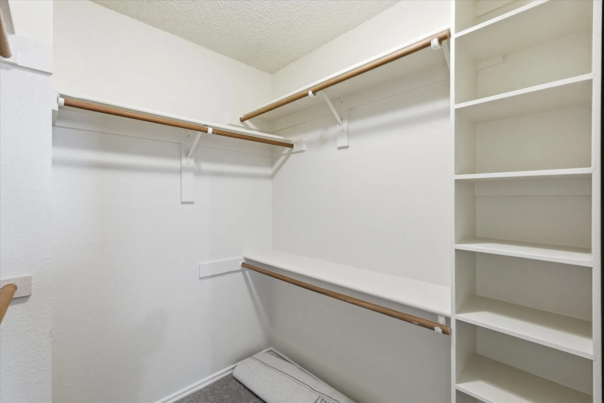 The roomy walk-in closet offers multiple hanging areas, built-in shelving and plenty of space for organized storage.