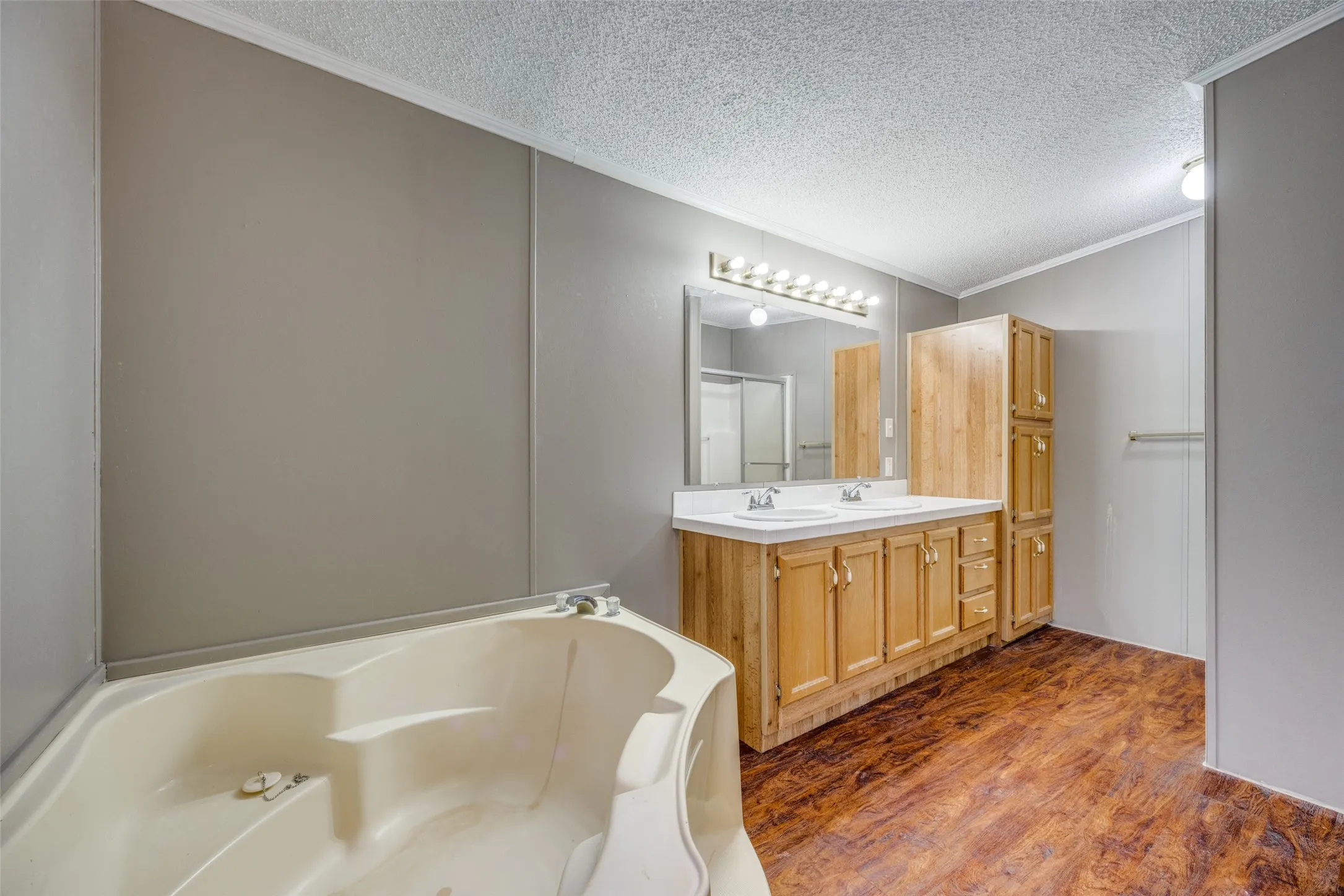Primary bath with double sinks, corner tub, and separate shower.