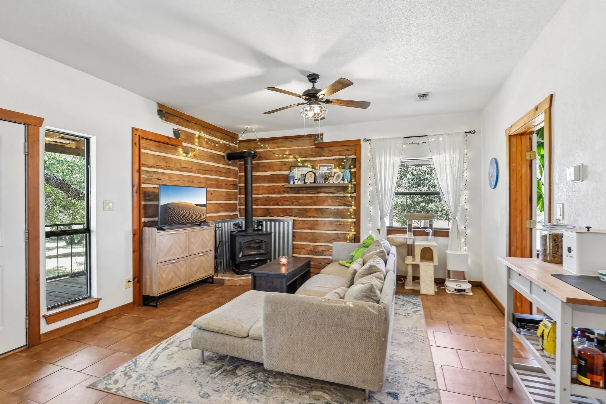 Living space featuring wood-finish accent wall, tile flooring, and a ceiling fan