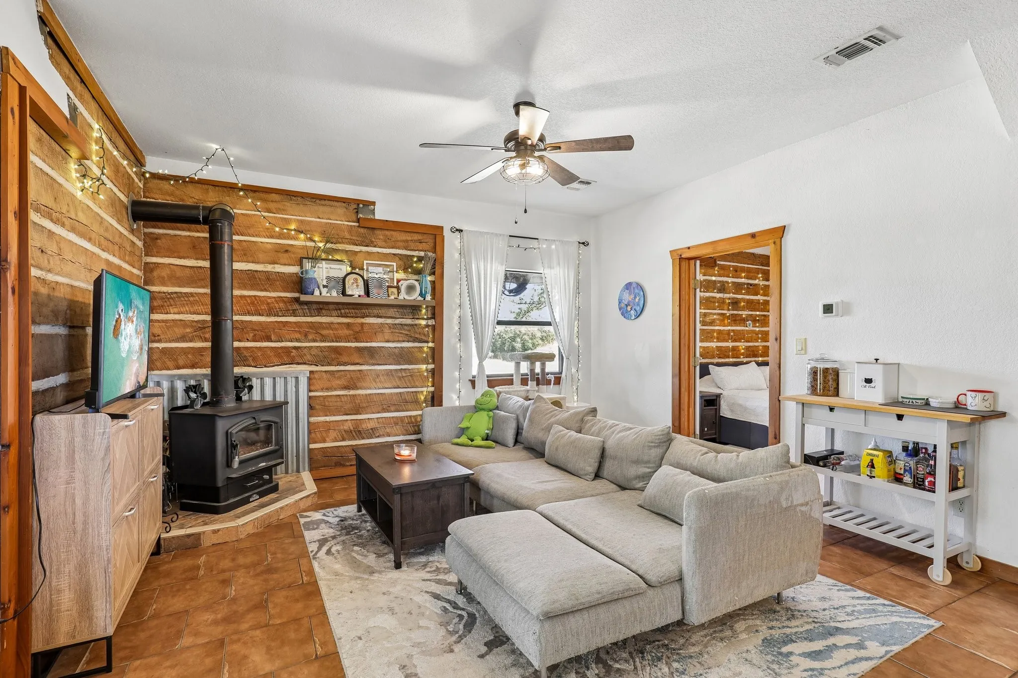 Living area featuring a prominent wood-burning stove on a raised hearth with coordinating tile