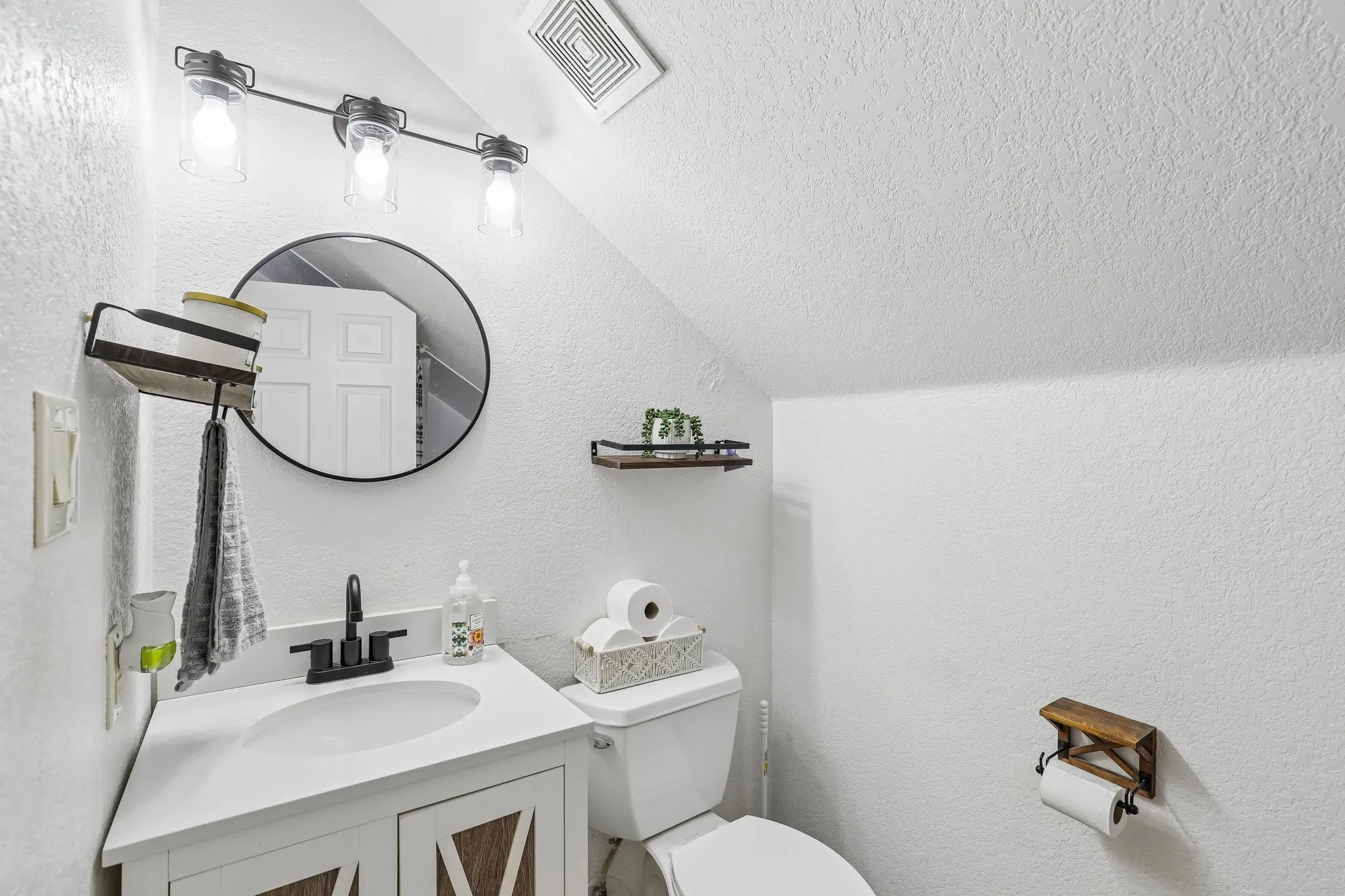 White vanity with a single basin sink and dark-finish faucet