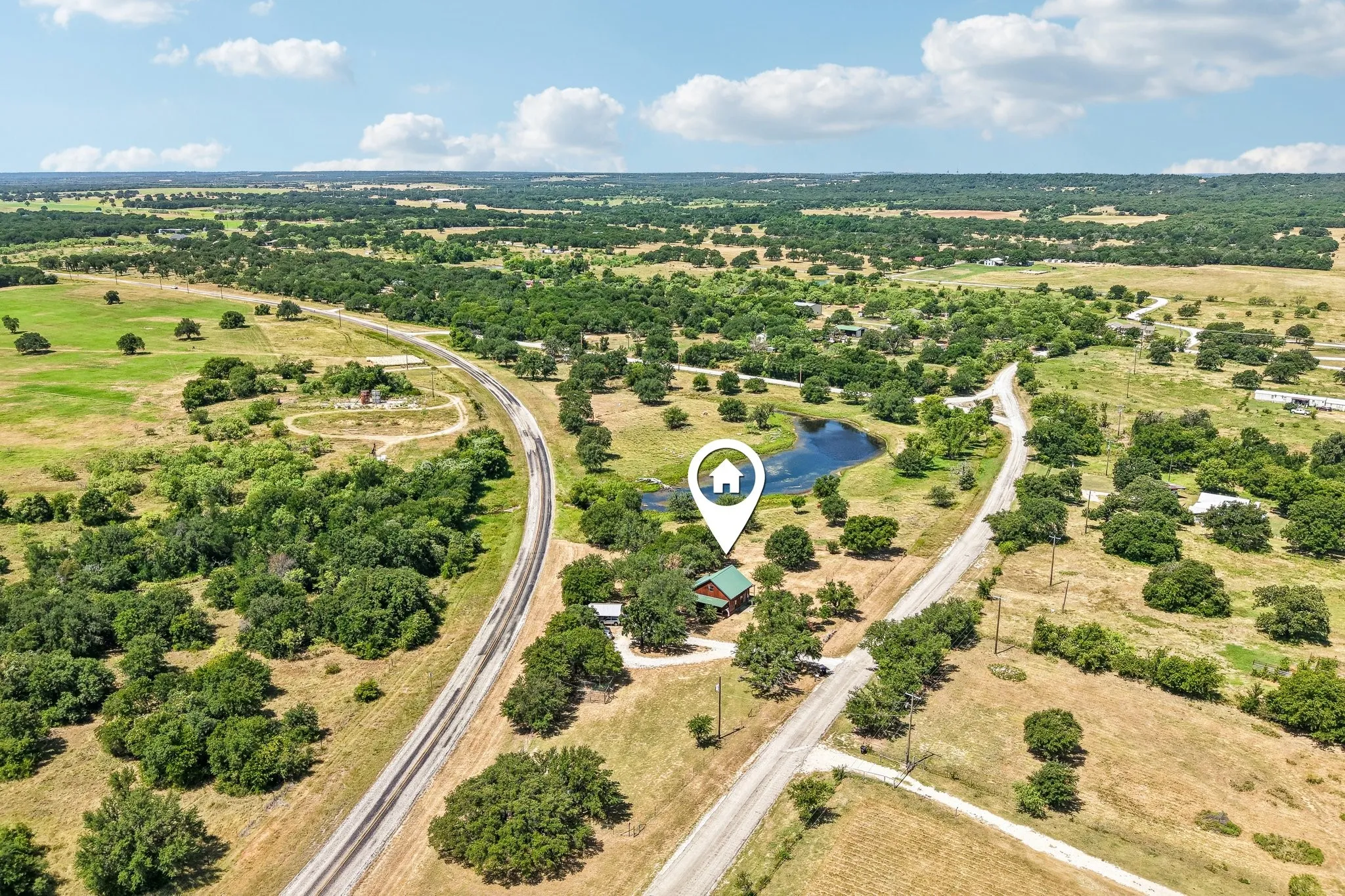 Expansive rural landscape featuring a private pond, mature trees, and a residential structure with a green roof