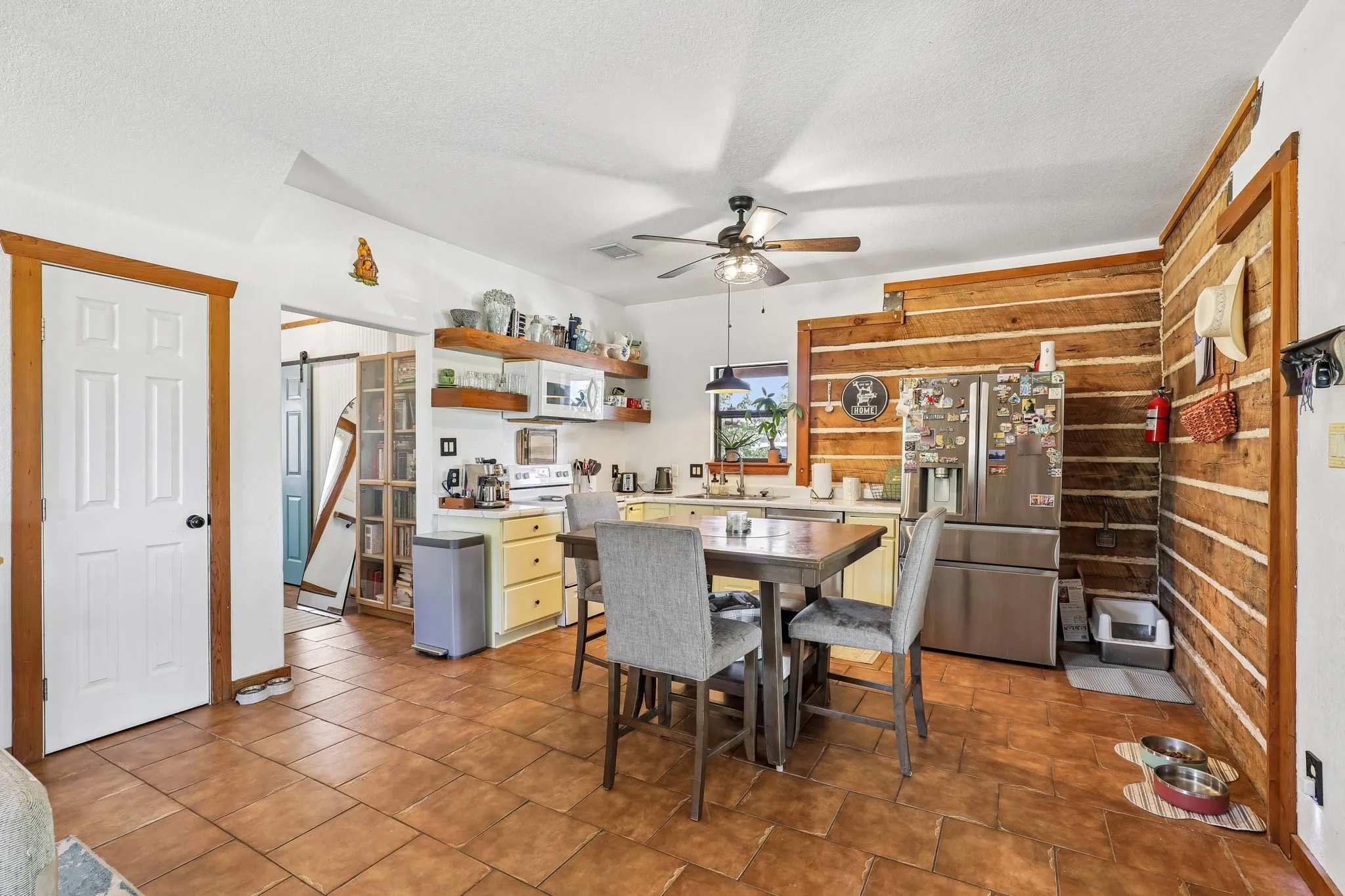 Kitchen featuring a log wall accent, tile flooring, and a ceiling fan