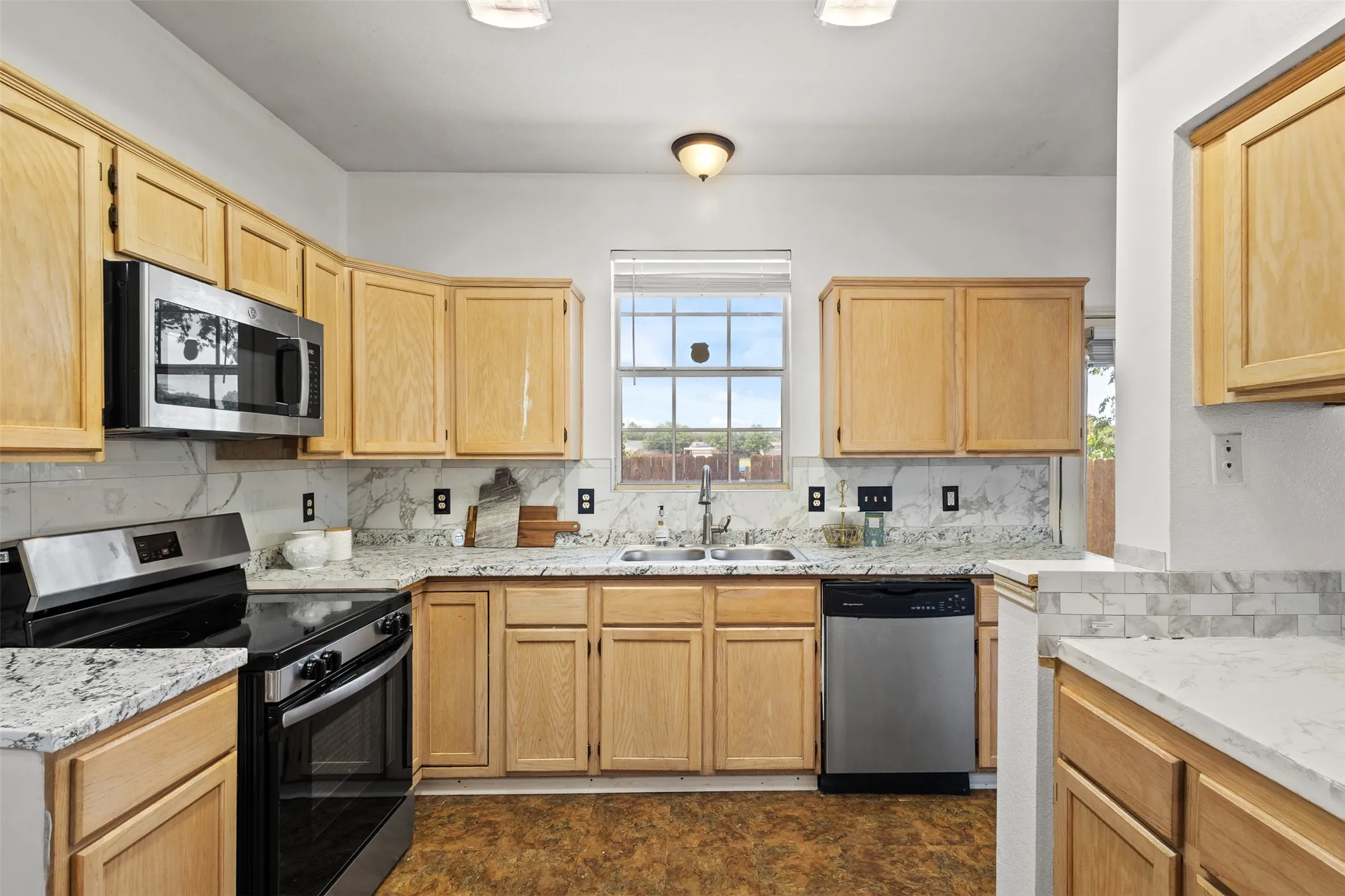 Kitchen featuring light wood cabinetry, white stone countertops, and stainless steel appliances
