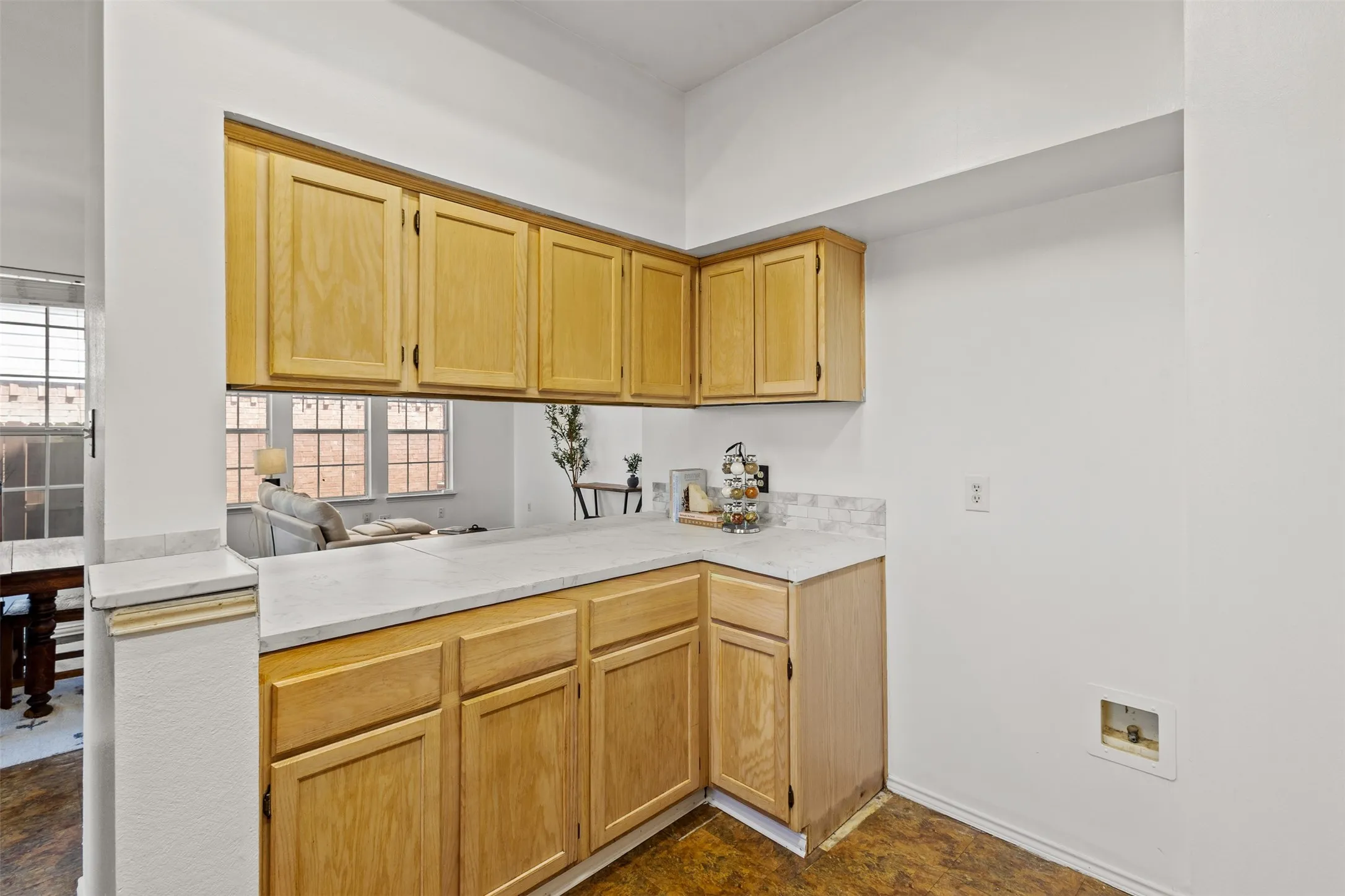 Kitchen featuring light wood cabinetry, light-toned countertops, and a tile backsplash