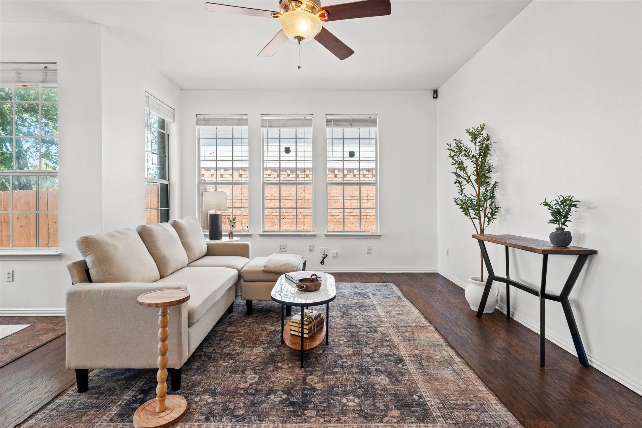 Spacious living area featuring wood-finish flooring, white painted walls, and ample natural light through multiple windows