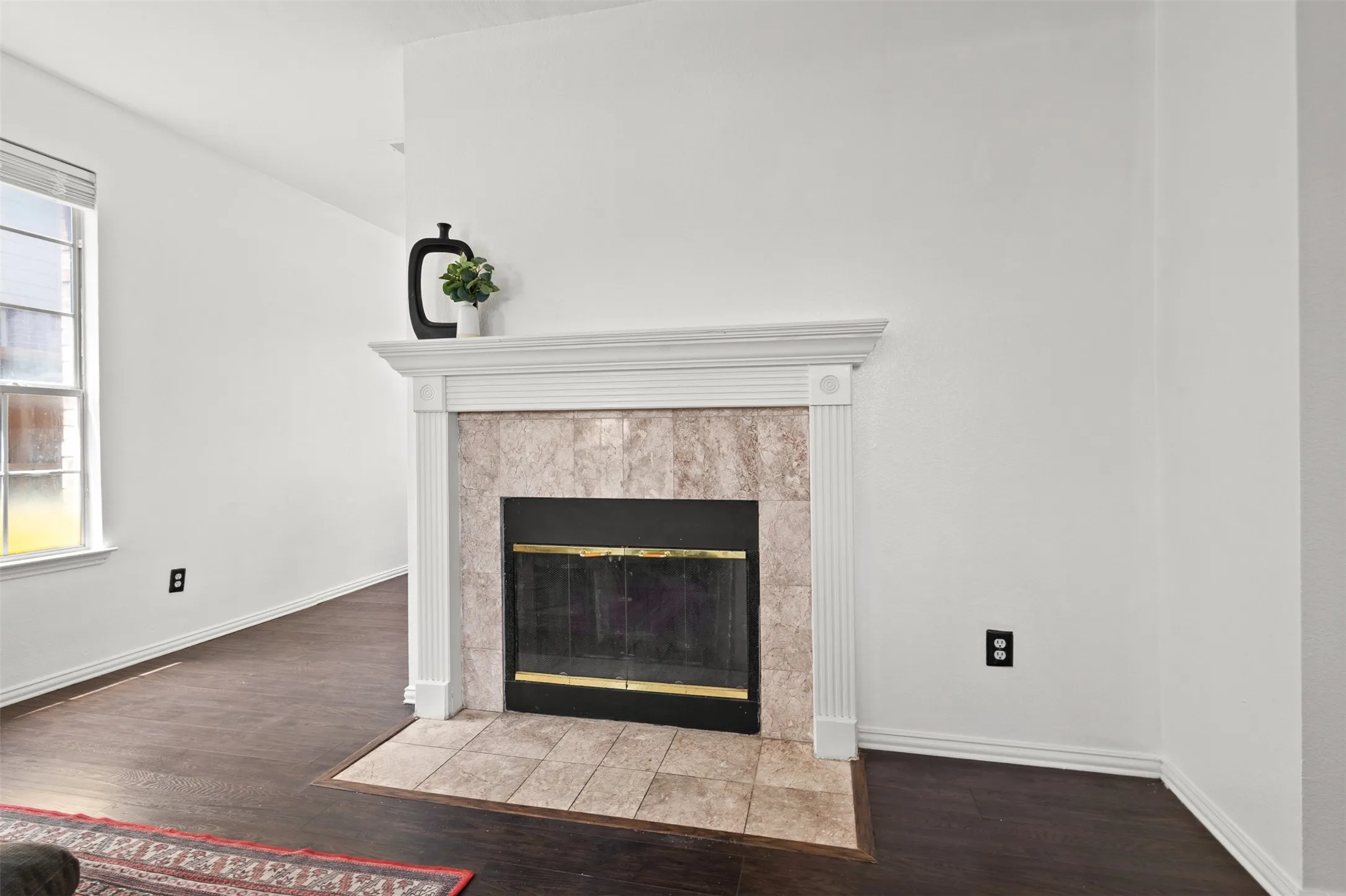 Fireplace with a decorative white mantel, fluted pilasters, and a stone-look tile surround