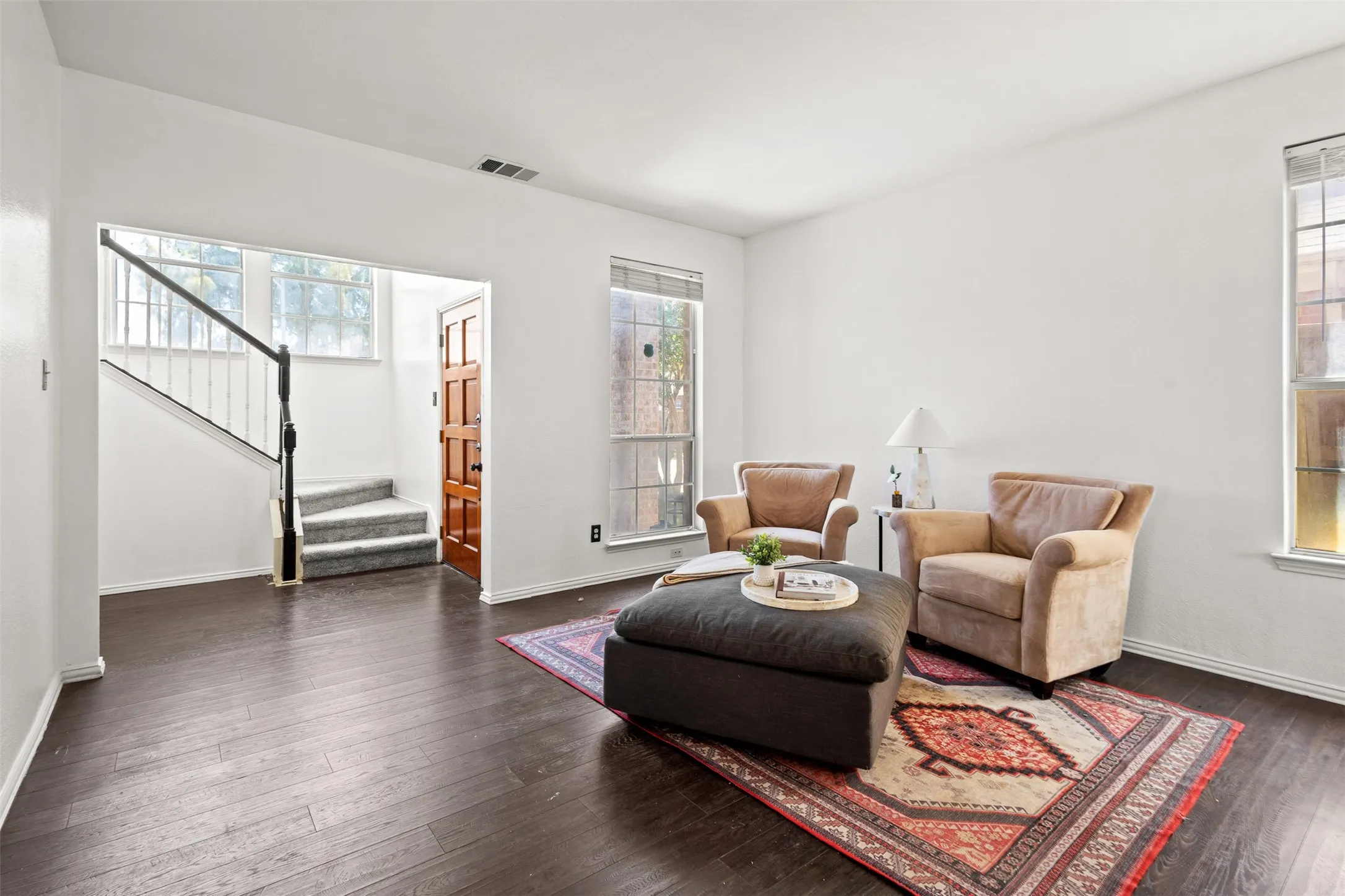 Spacious living area featuring dark wood-finish flooring and bright white walls
