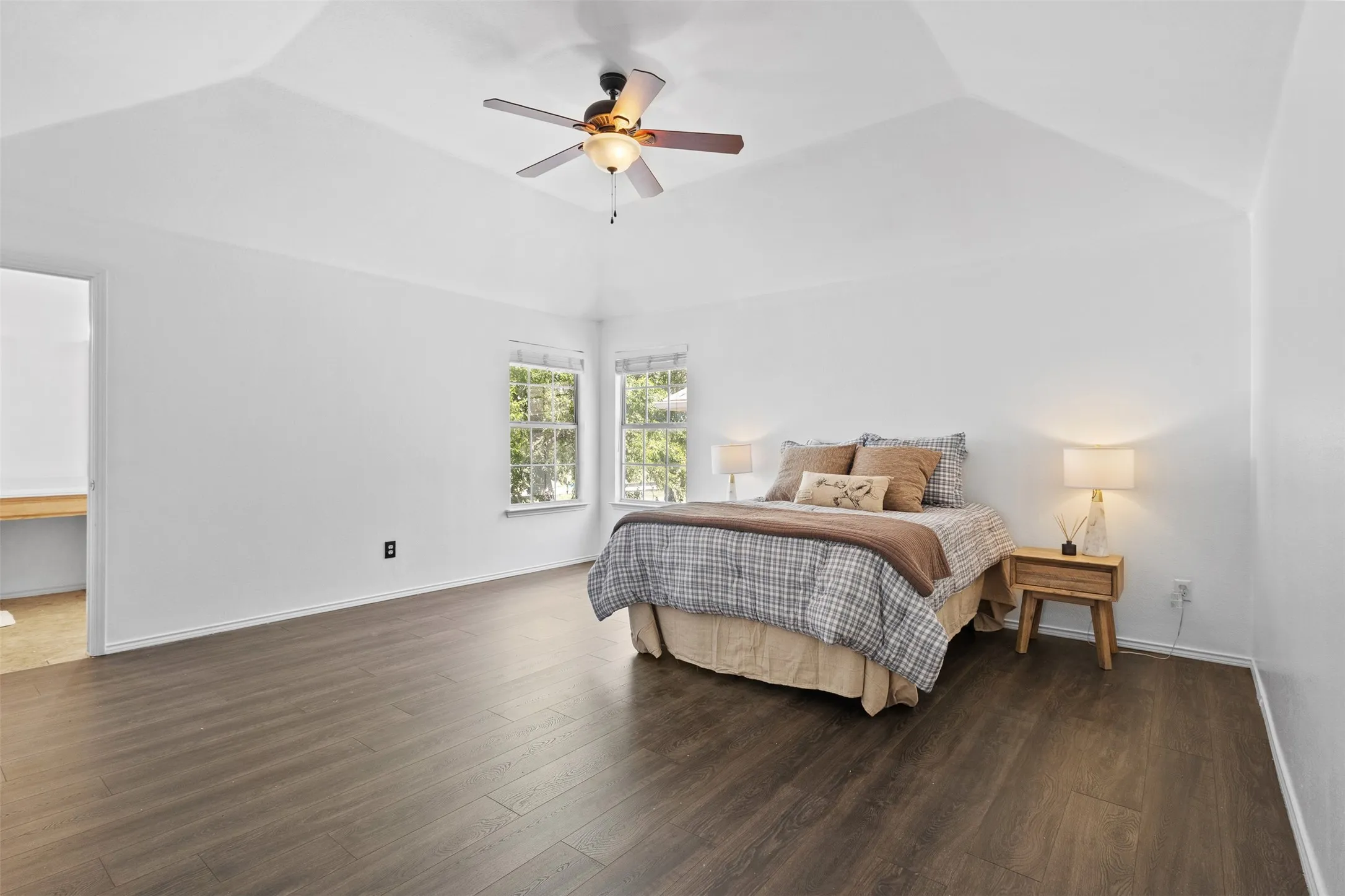 Spacious room featuring vaulted ceilings, a ceiling fan, and wood-finish flooring