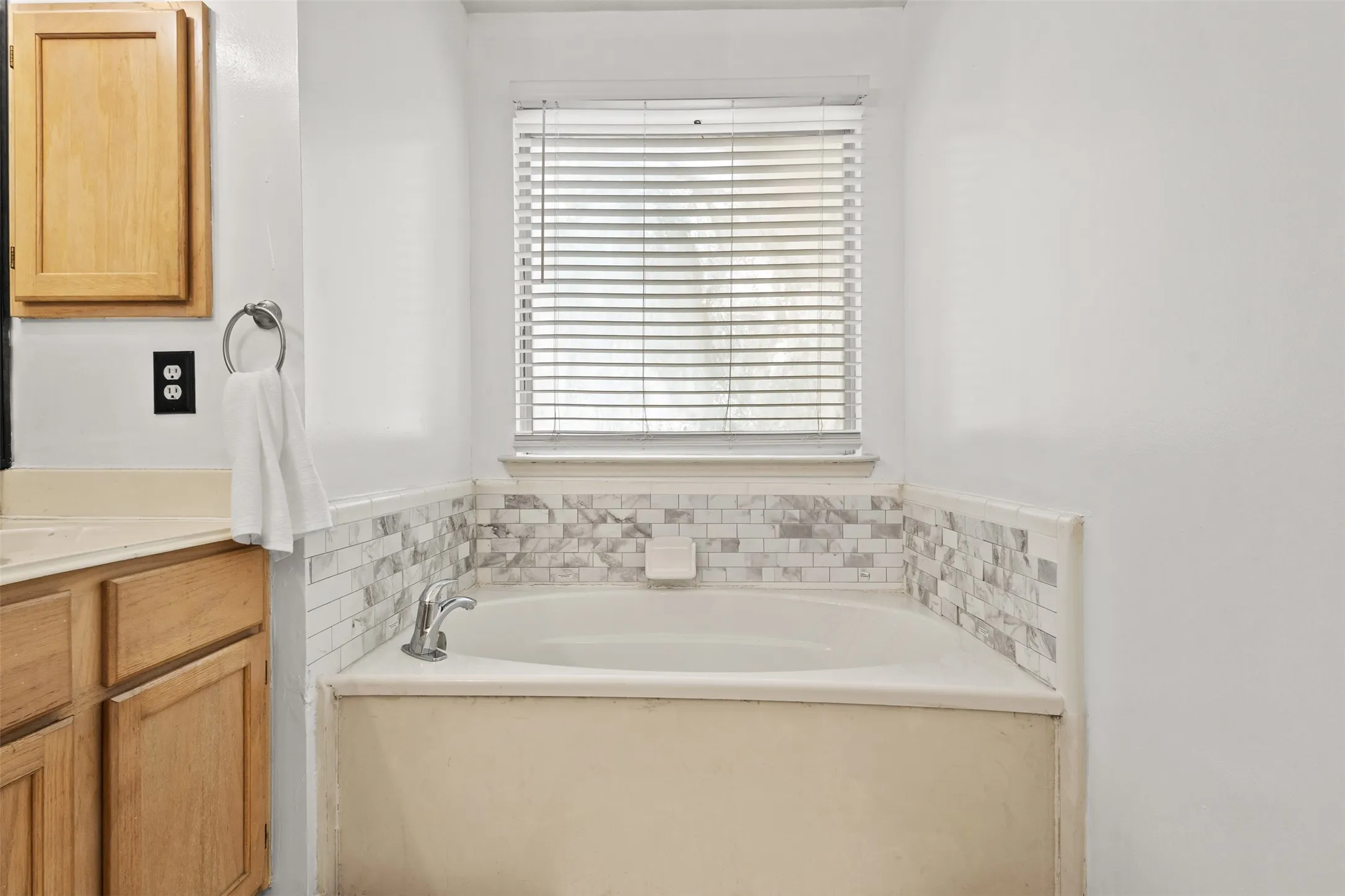 Built-in soaking tub with a tiled surround featuring varied grey and white mosaic tiles