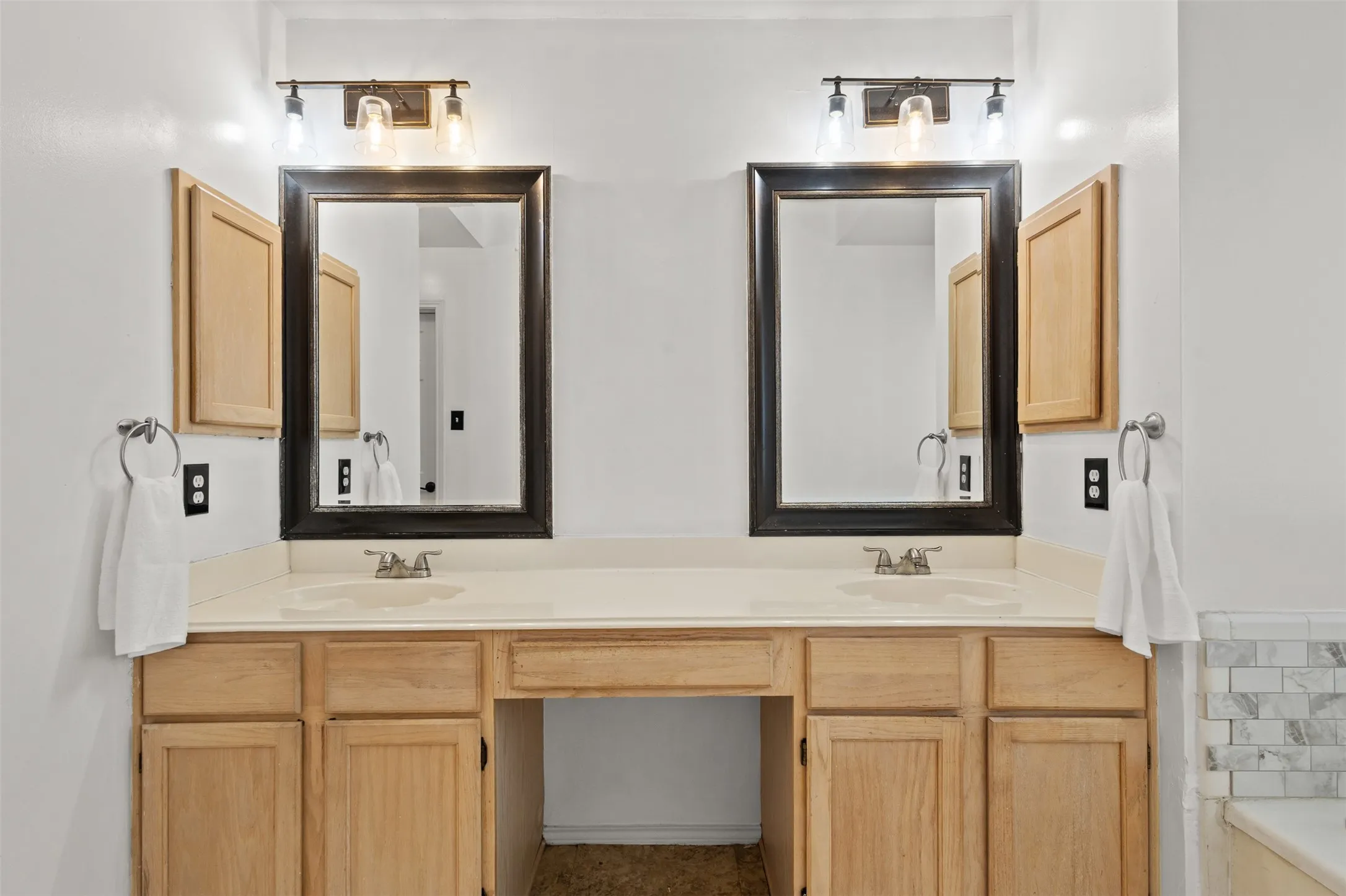 Dual vanity with natural wood-finish cabinetry and light-toned countertops