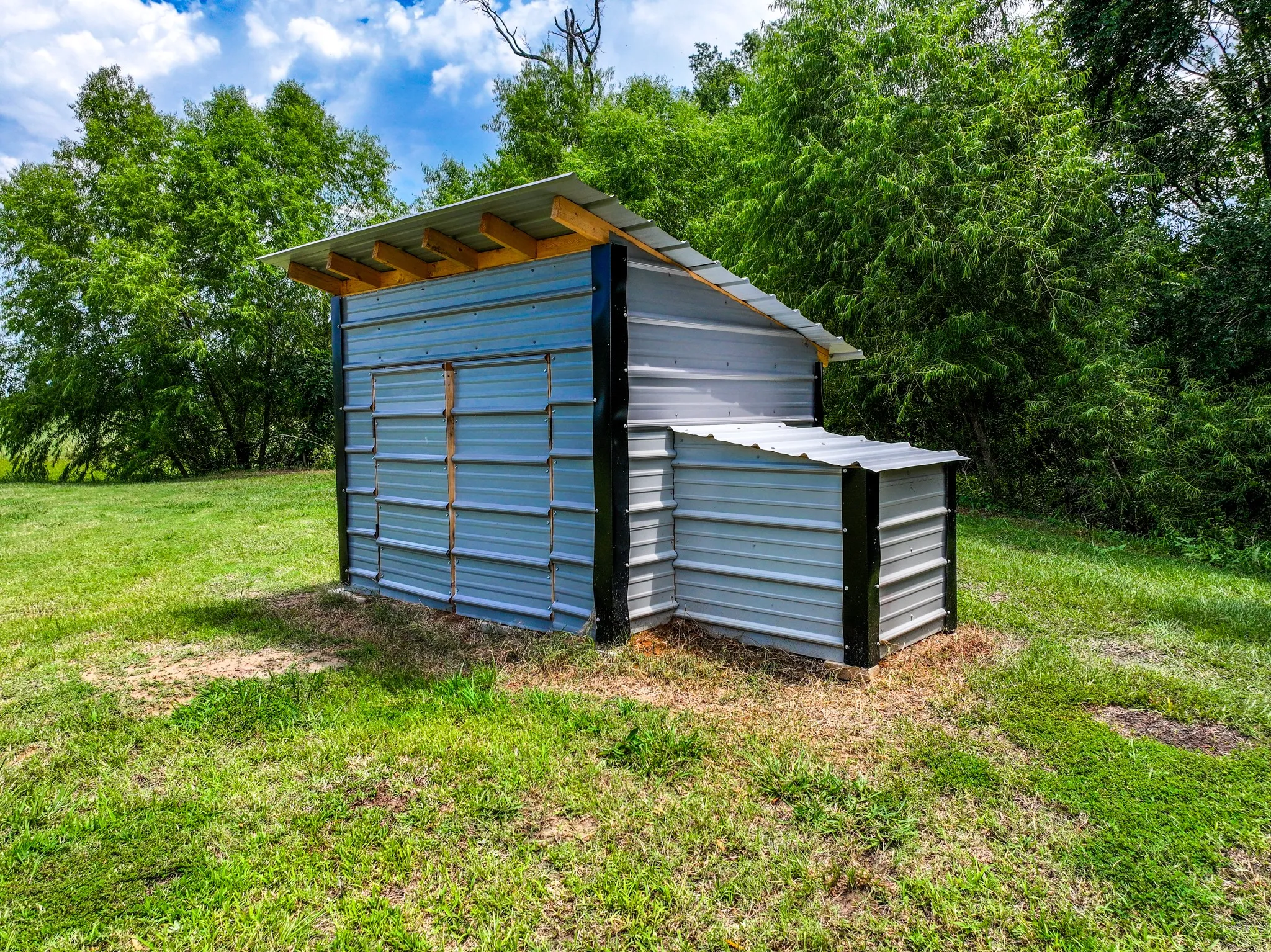 Corrugated metal structure with a sloped metal roof and exposed wood framing