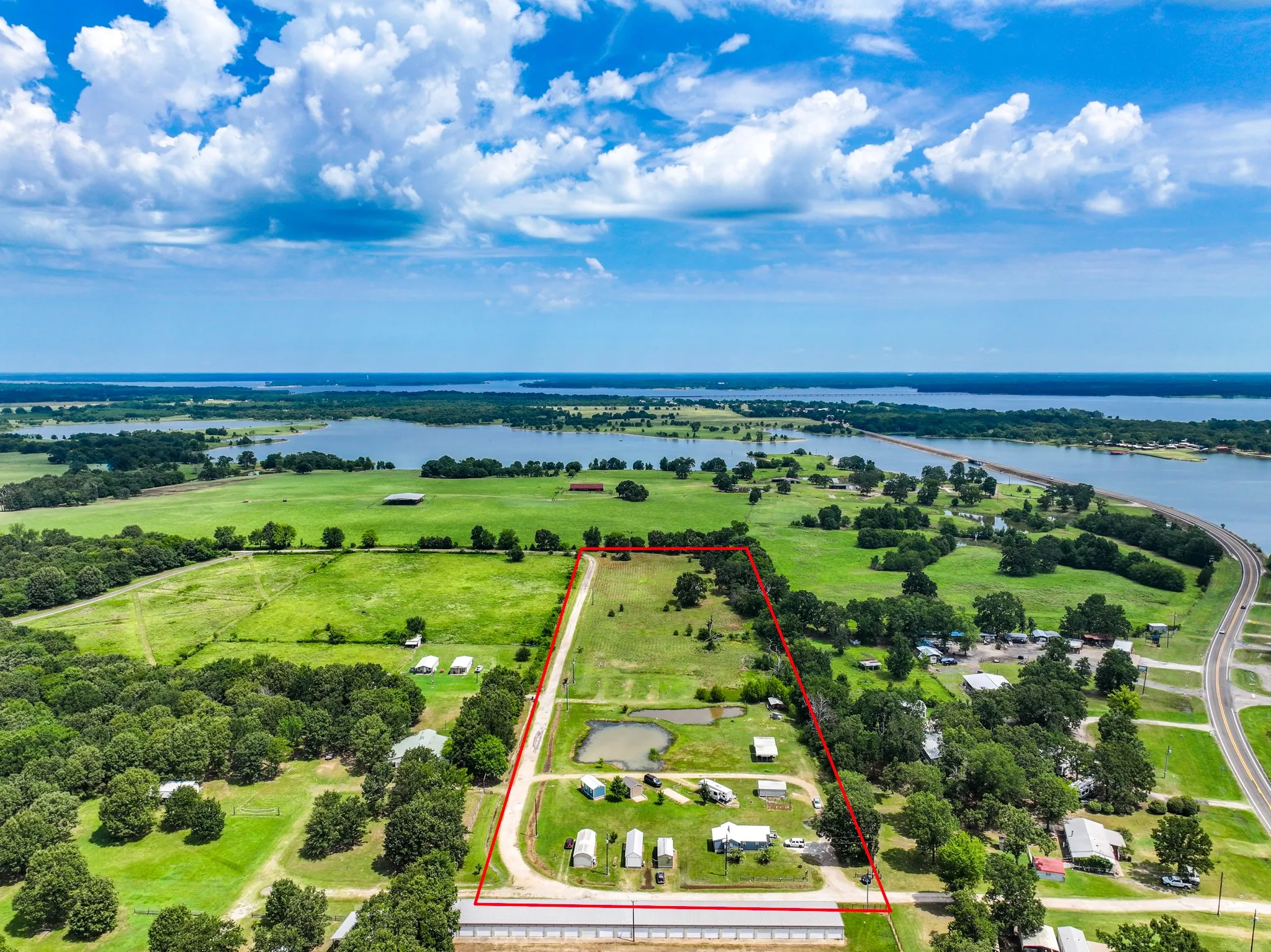 Expansive rural property featuring a long driveway, multiple outbuildings, two ponds, and a large barn structure