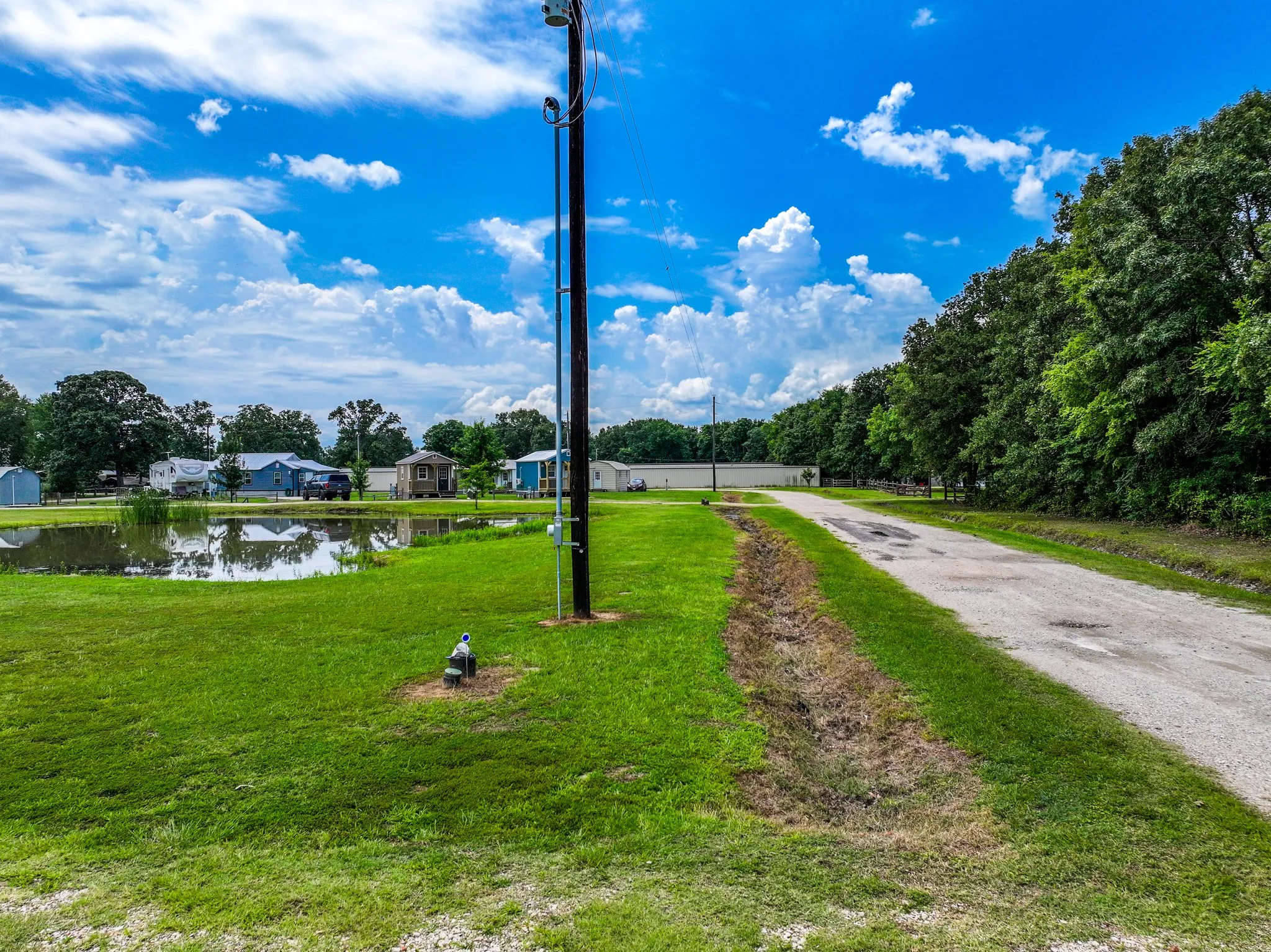 Grassed lot featuring a private pond and a gravel drive
