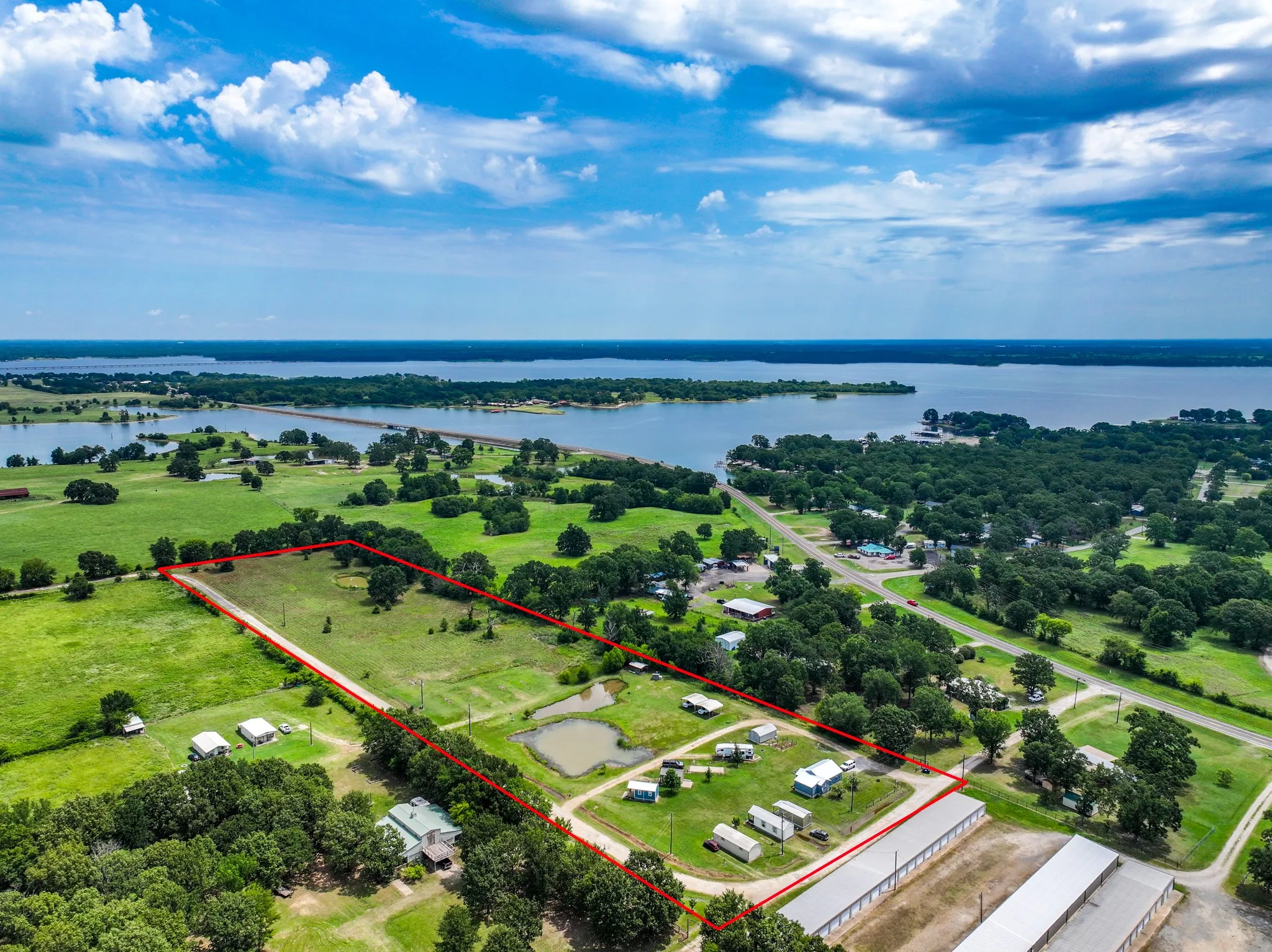 Expansive parcel featuring a large pond and mature trees, bordered by a clear roadway
