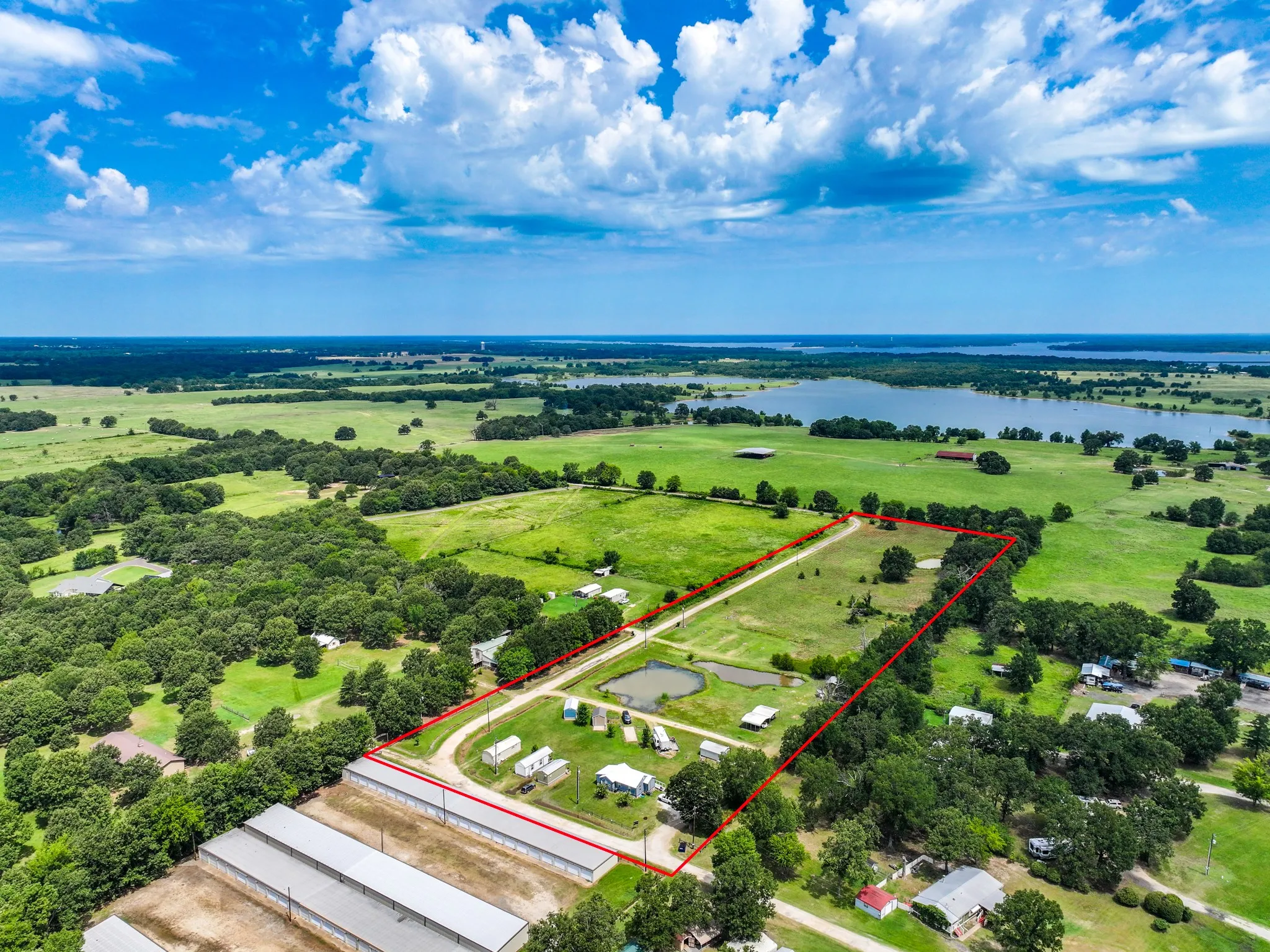 Expansive land parcel featuring open fields, mature trees, a private pond, and proximity to a large body of water
