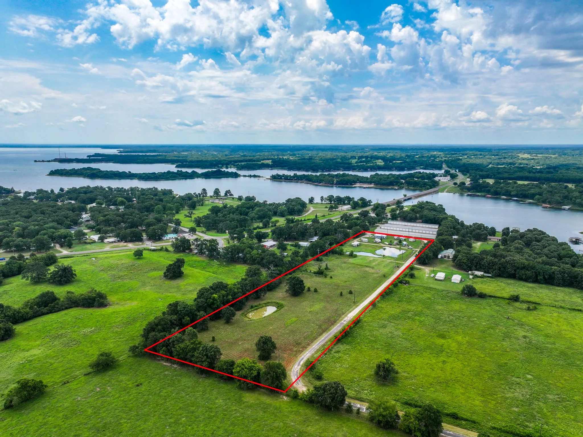 Expansive land parcel featuring a private pond, mature trees, and direct water frontage