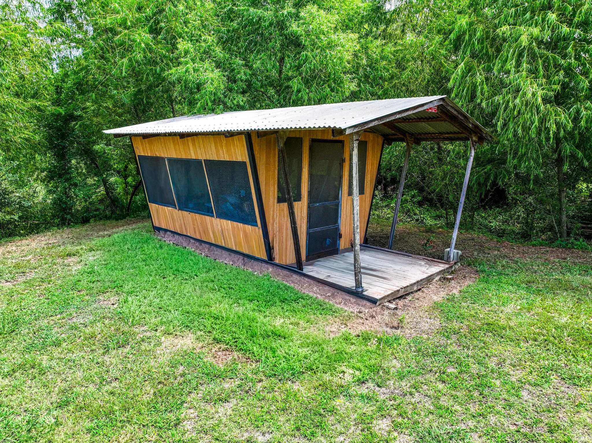 Compact structure featuring wood-finish siding, a corrugated metal roof, and a covered porch area
