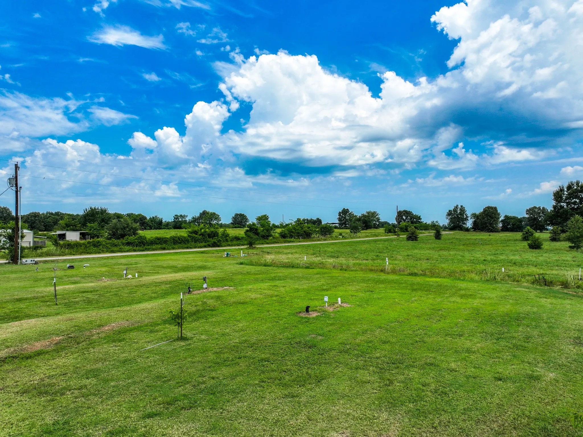 Expansive green space featuring scattered trees and utility hookups