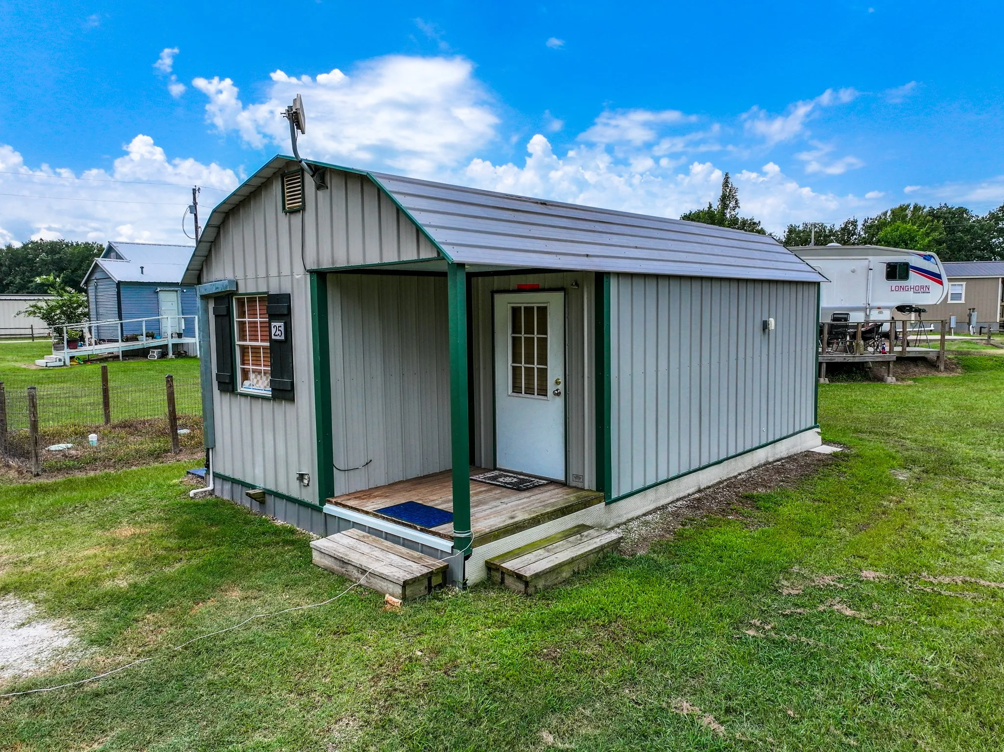 Compact structure featuring a light gray vertical siding exterior with green trim