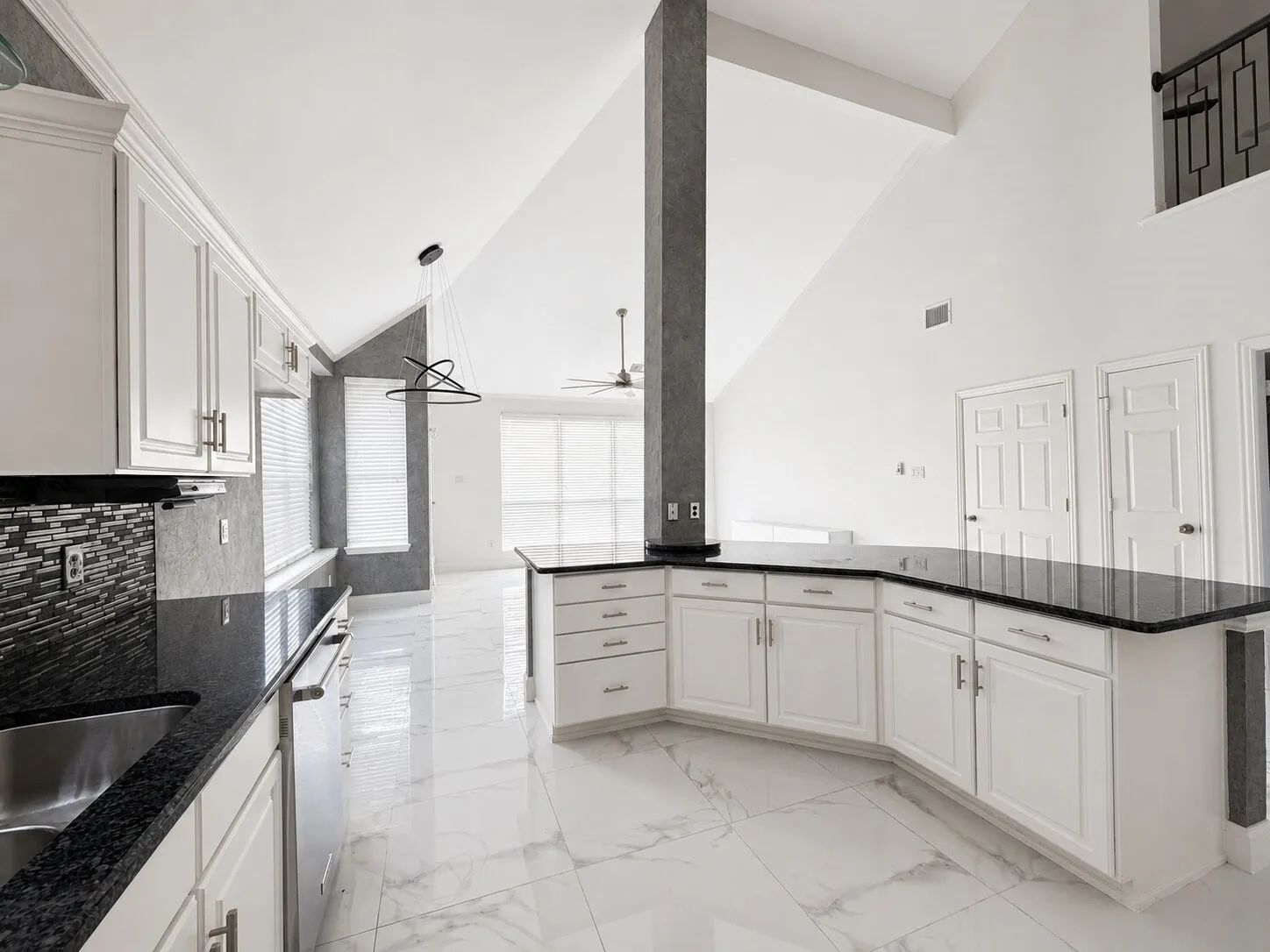 Kitchen featuring white cabinetry with brushed nickel hardware, dark stone countertops, and a mosaic tile backsplash