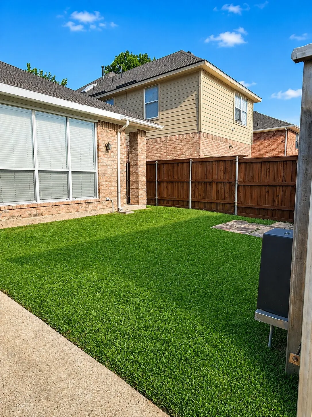 Private backyard featuring a vibrant lawn and a wood privacy fence