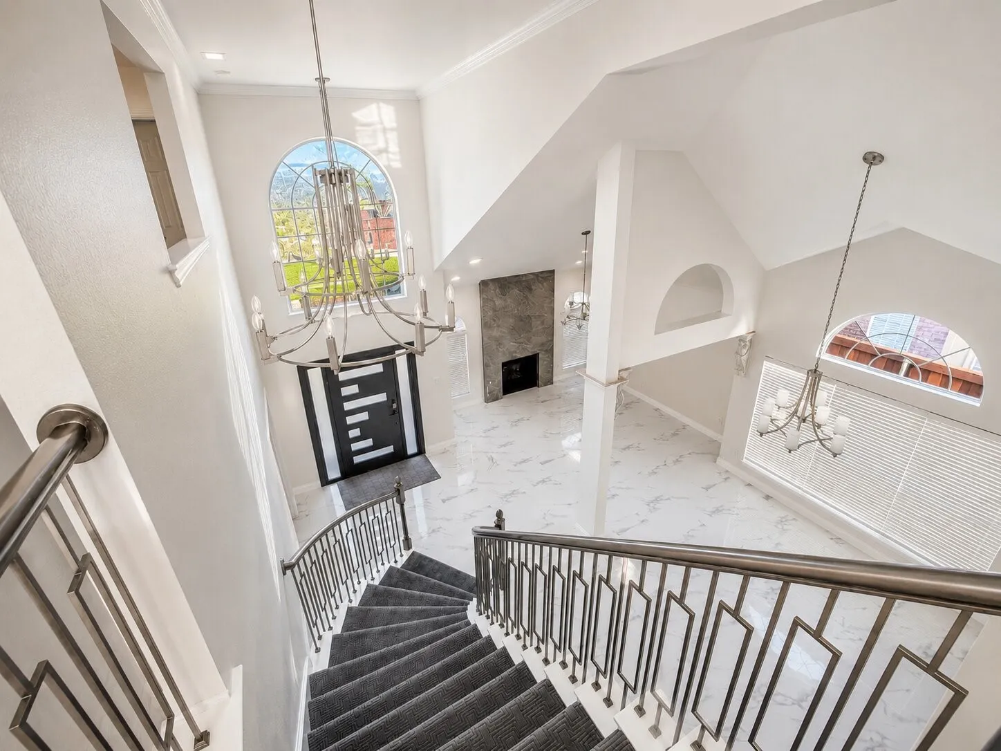 Grand foyer with high ceilings and a curved staircase featuring custom metal railings