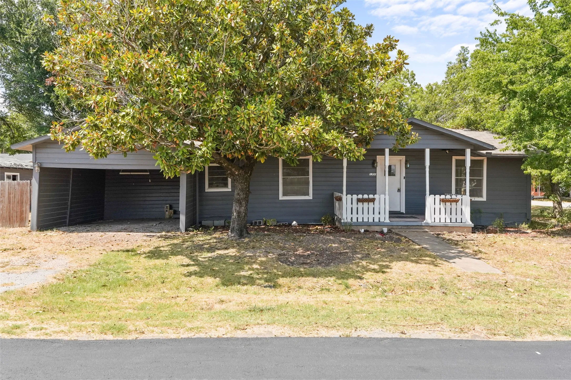 Single-story residence featuring a covered entry, white porch railings, and a side carport