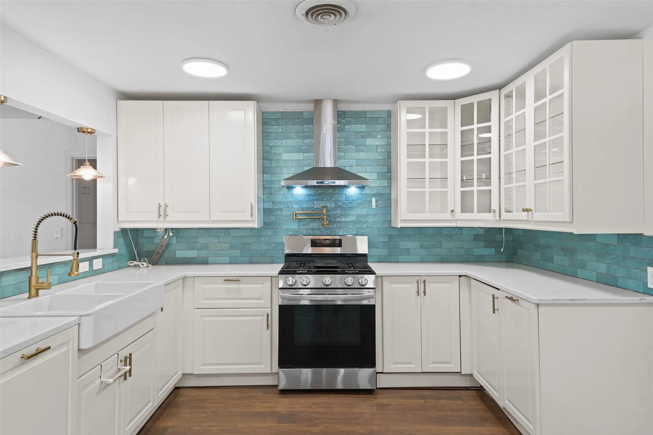 White shaker-style cabinetry with gold-tone hardware, white countertops, a deep farmhouse sink with a gold-tone pull-down faucet, and a subway tile backsplash