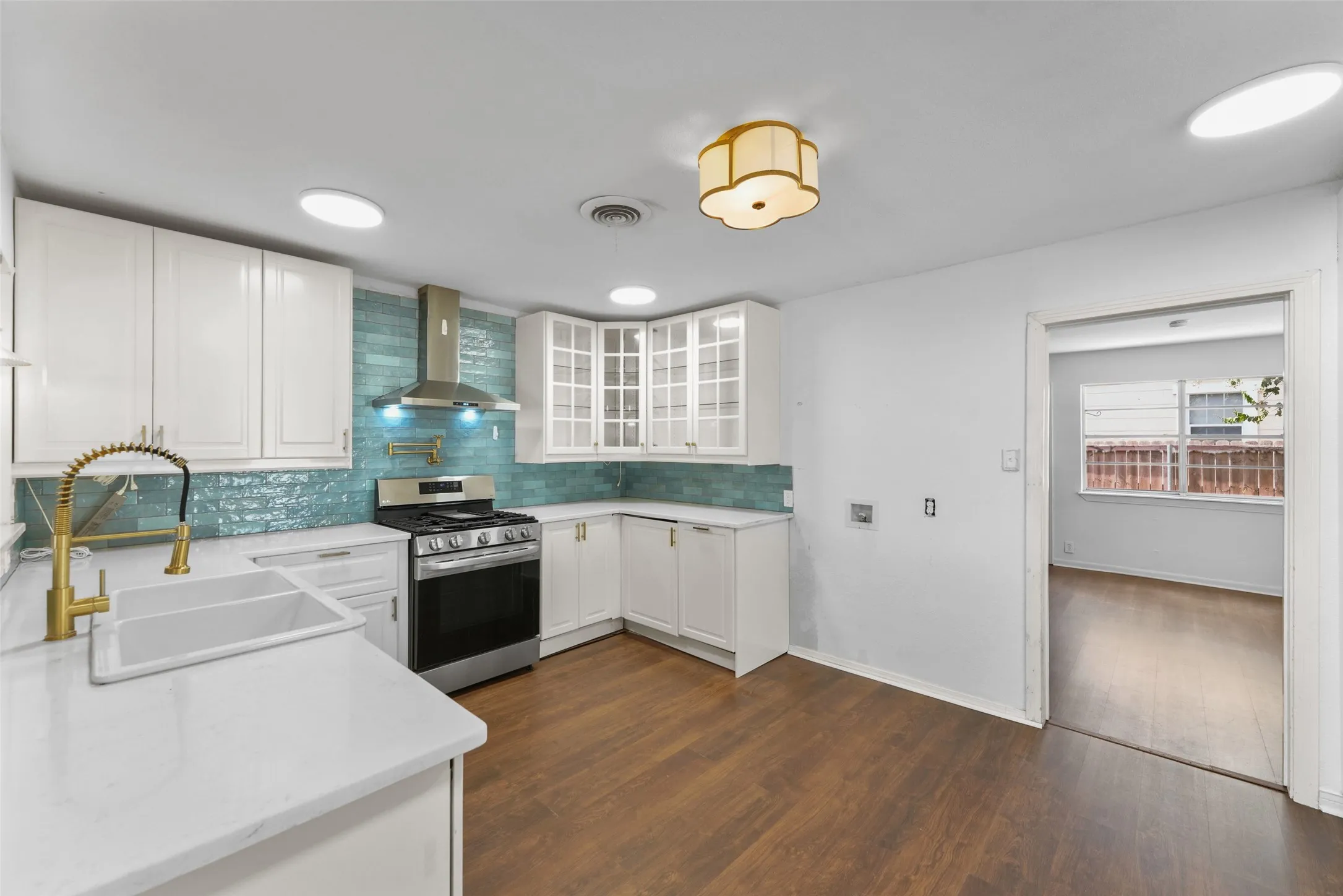 Kitchen featuring white cabinetry, a teal tile backsplash, stainless steel range with matching hood, white countertops, and wood-finish flooring