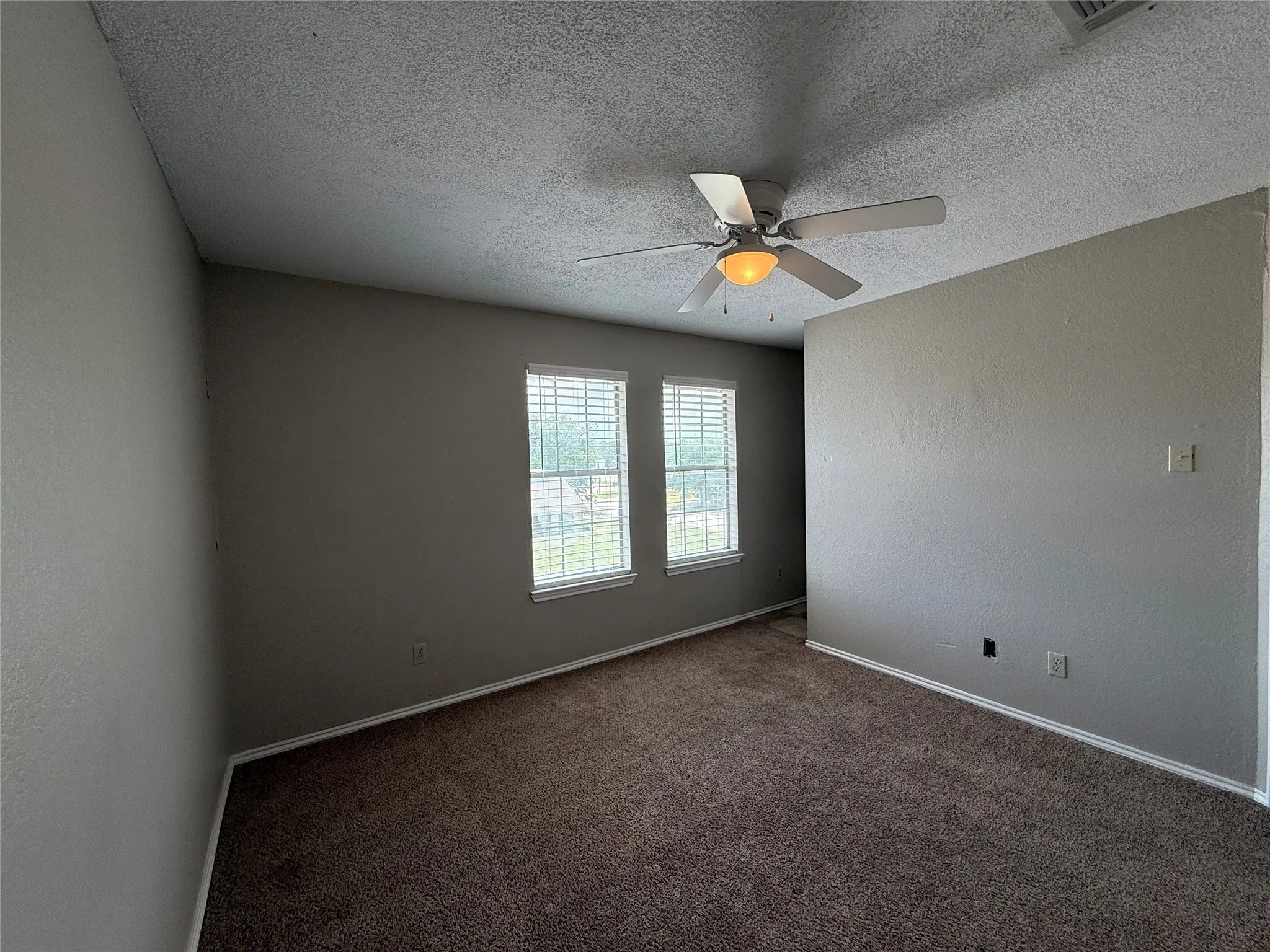 Unfurnished room featuring ceiling fan, carpet flooring, and a textured ceiling