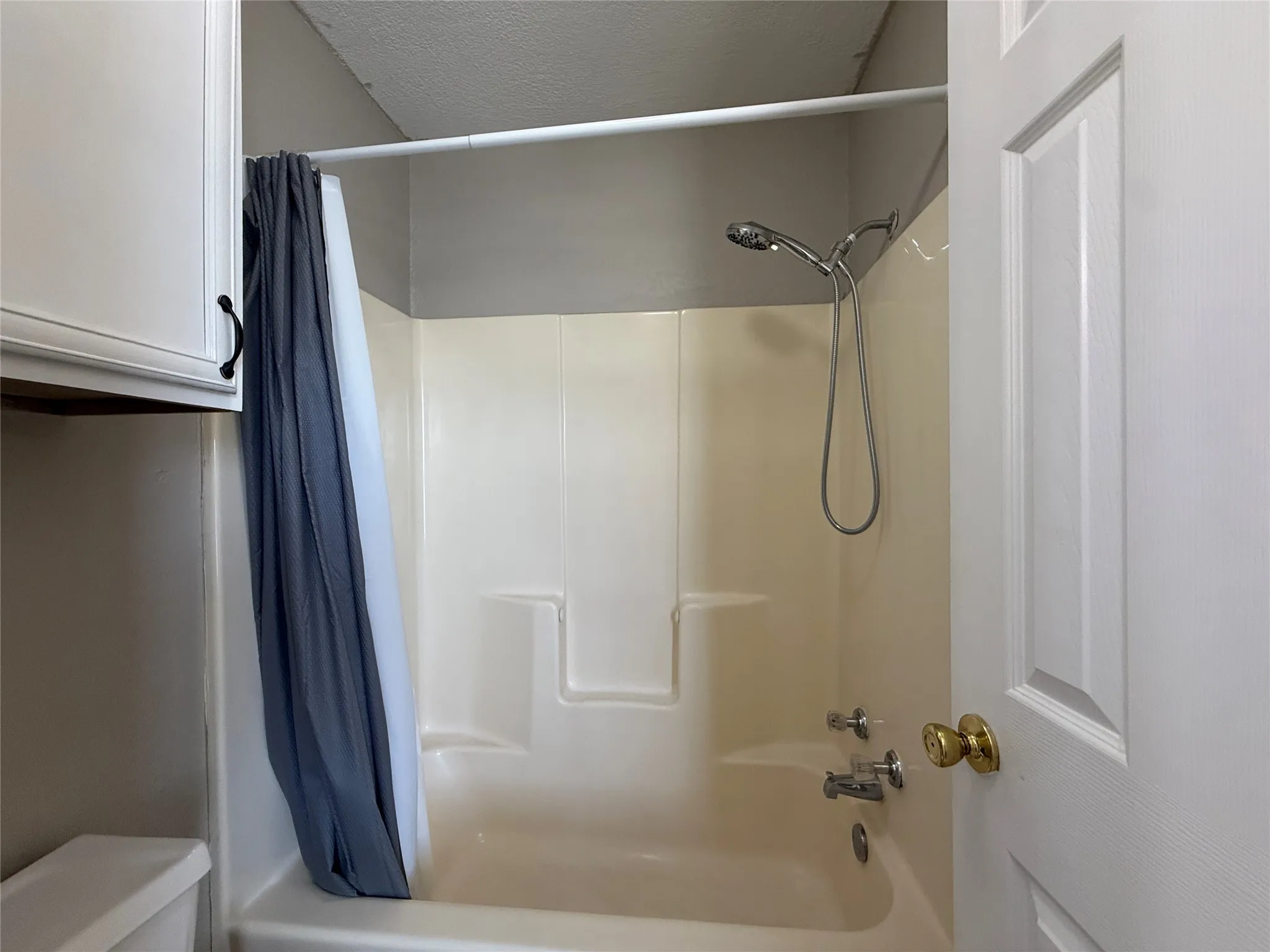 Bathroom featuring shower / bath combination with curtain and toilet