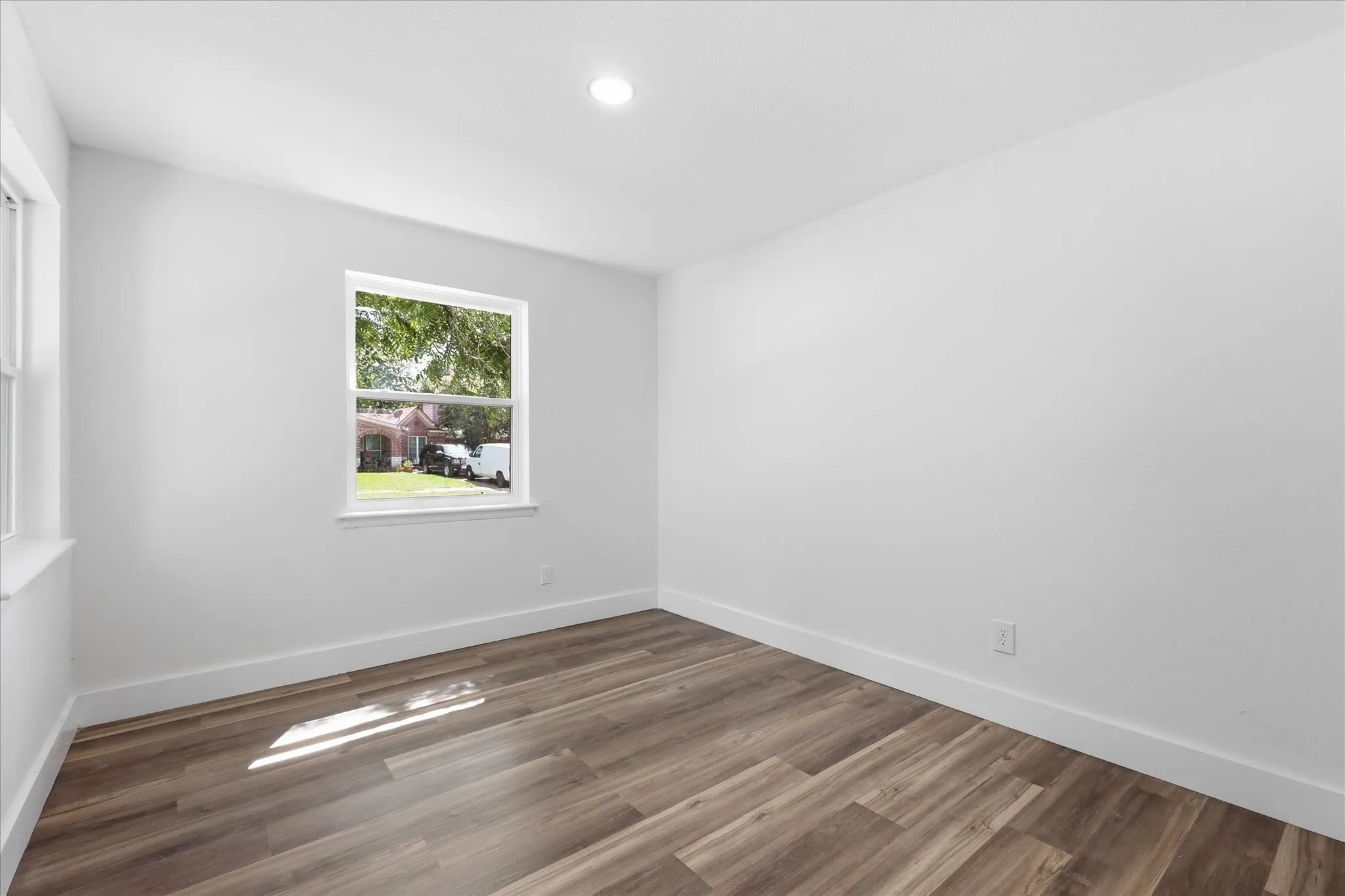 Bright interior space featuring wood-finish flooring, white walls, and a recessed ceiling light