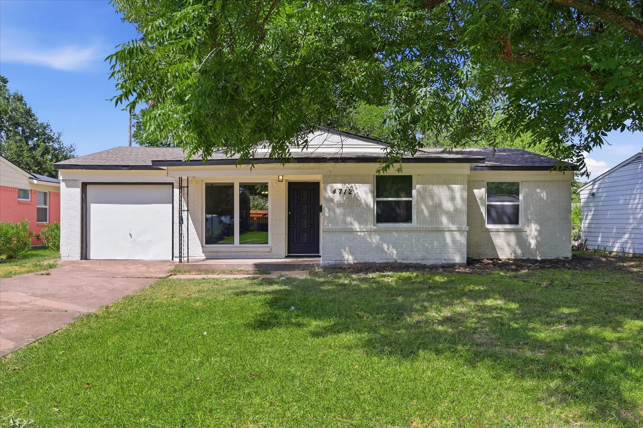 Single-story residence featuring a white painted brick exterior, a driveway, and an attached garage