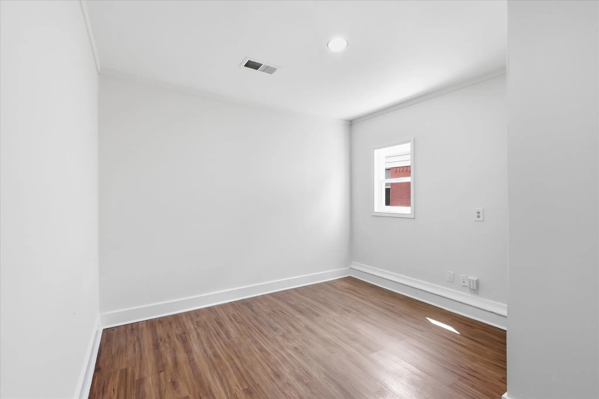 Room featuring wood-finish flooring, white baseboards, crown molding, a recessed ceiling light, and a single window